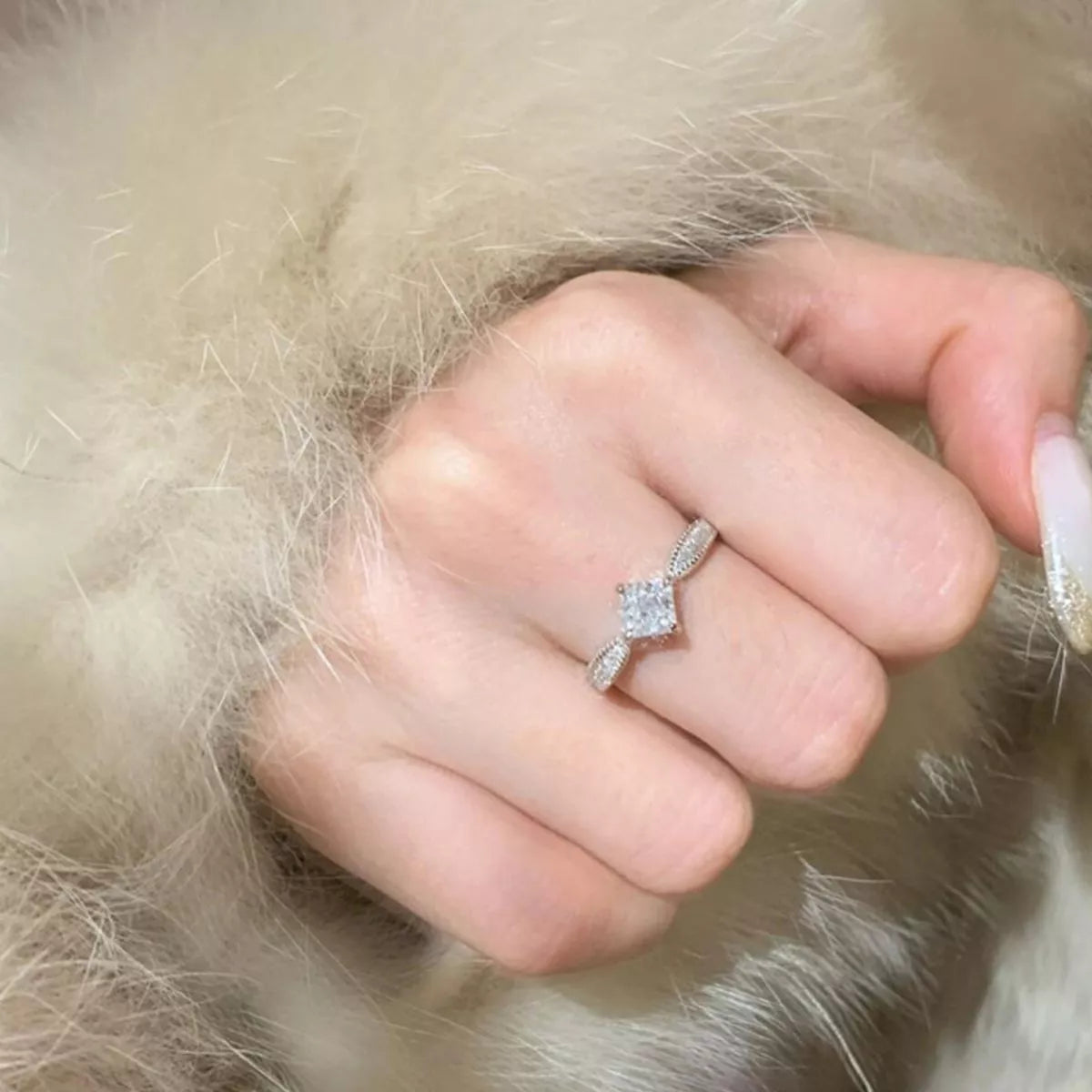 Hand wearing a diamond ring on a fur background