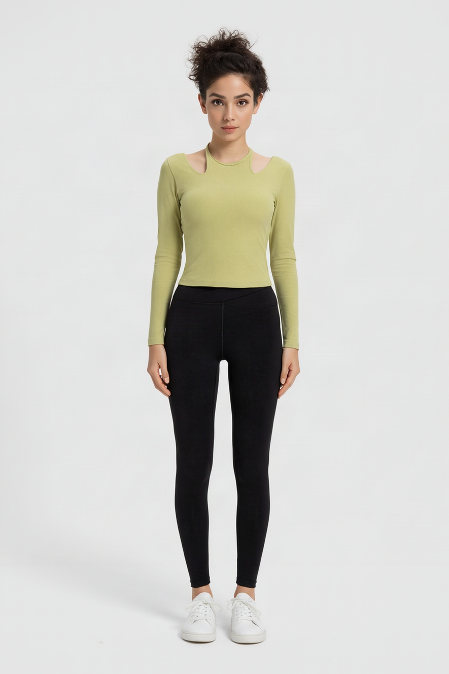 Sage green cutout shoulder top with black leggings, white sneakers, hair in a bun