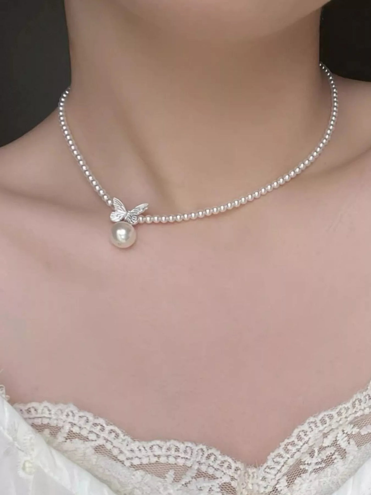 Pearl necklace with a pendant on a model wearing a lace top.