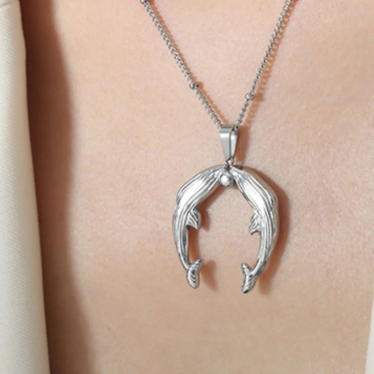 Kissing Dolphins Silver Plated Necklace On Model Neckline Closeup Shot | Rebellious Gal Jewelry