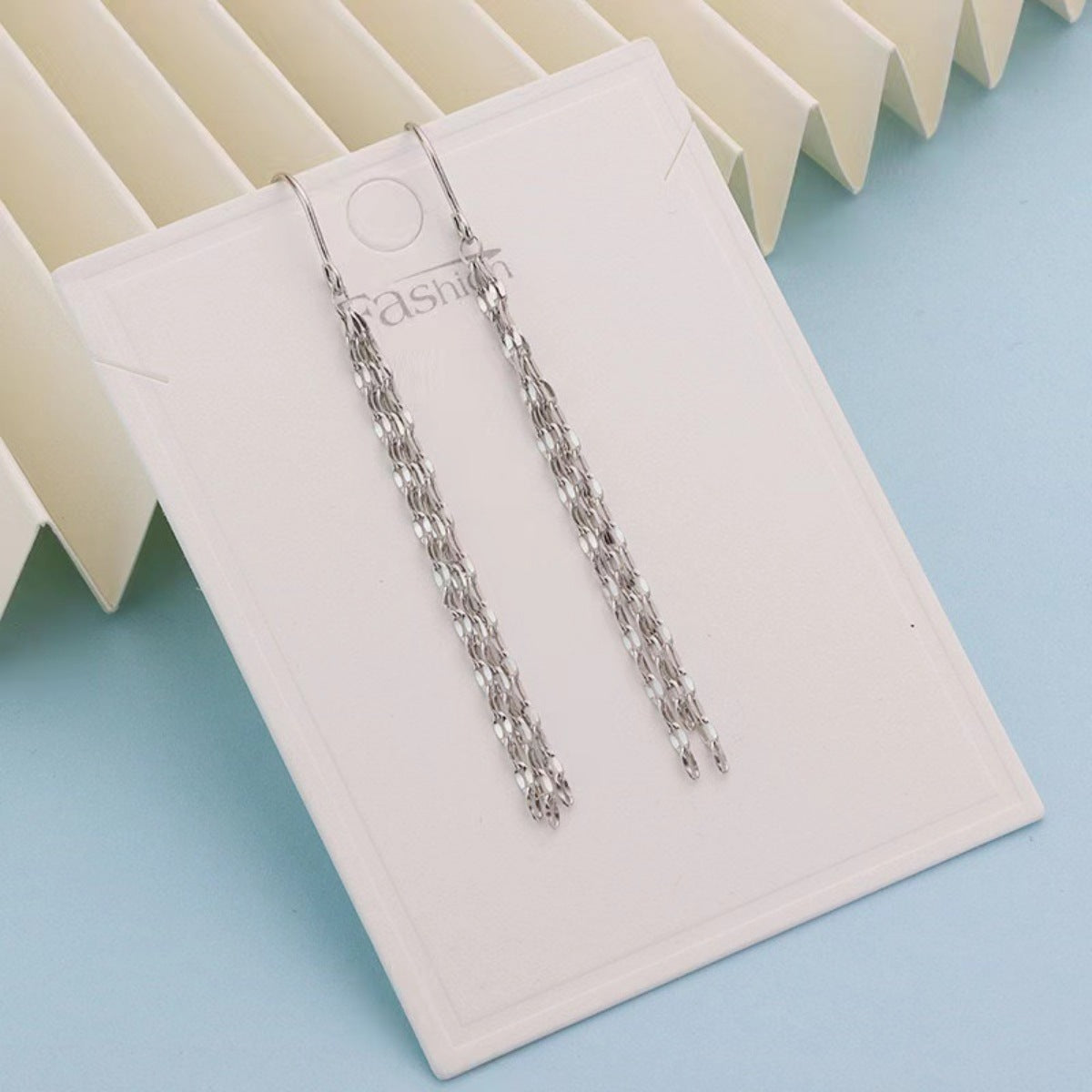 Silver chain earrings on a white display card with a light blue background