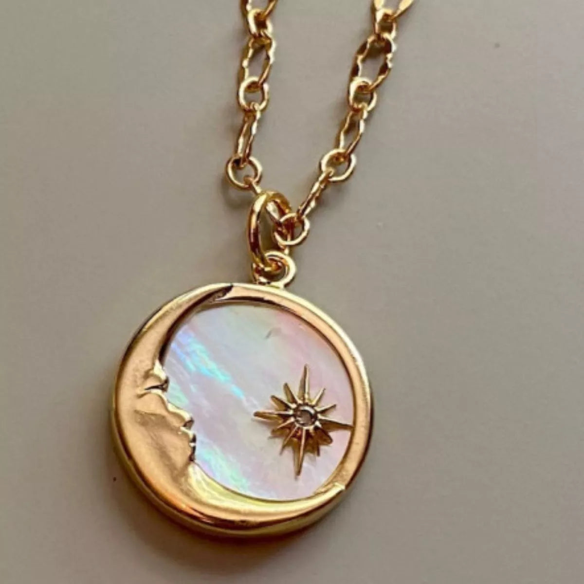 Gold necklace with a moon and star pendant on a neutral background