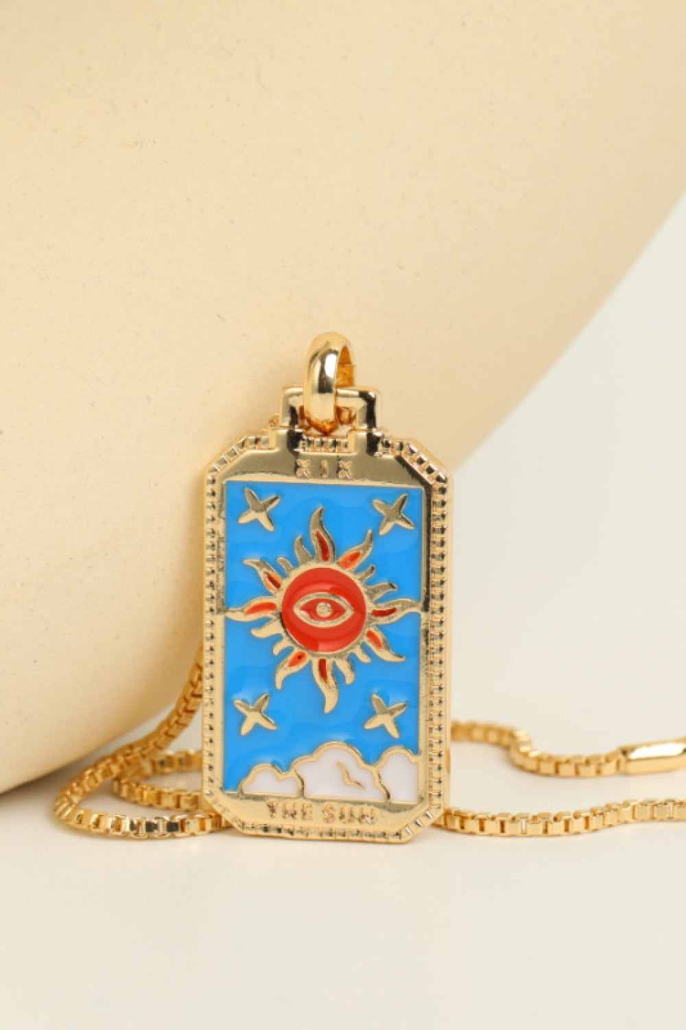 Necklace with a sun and eye pendant on a beige background