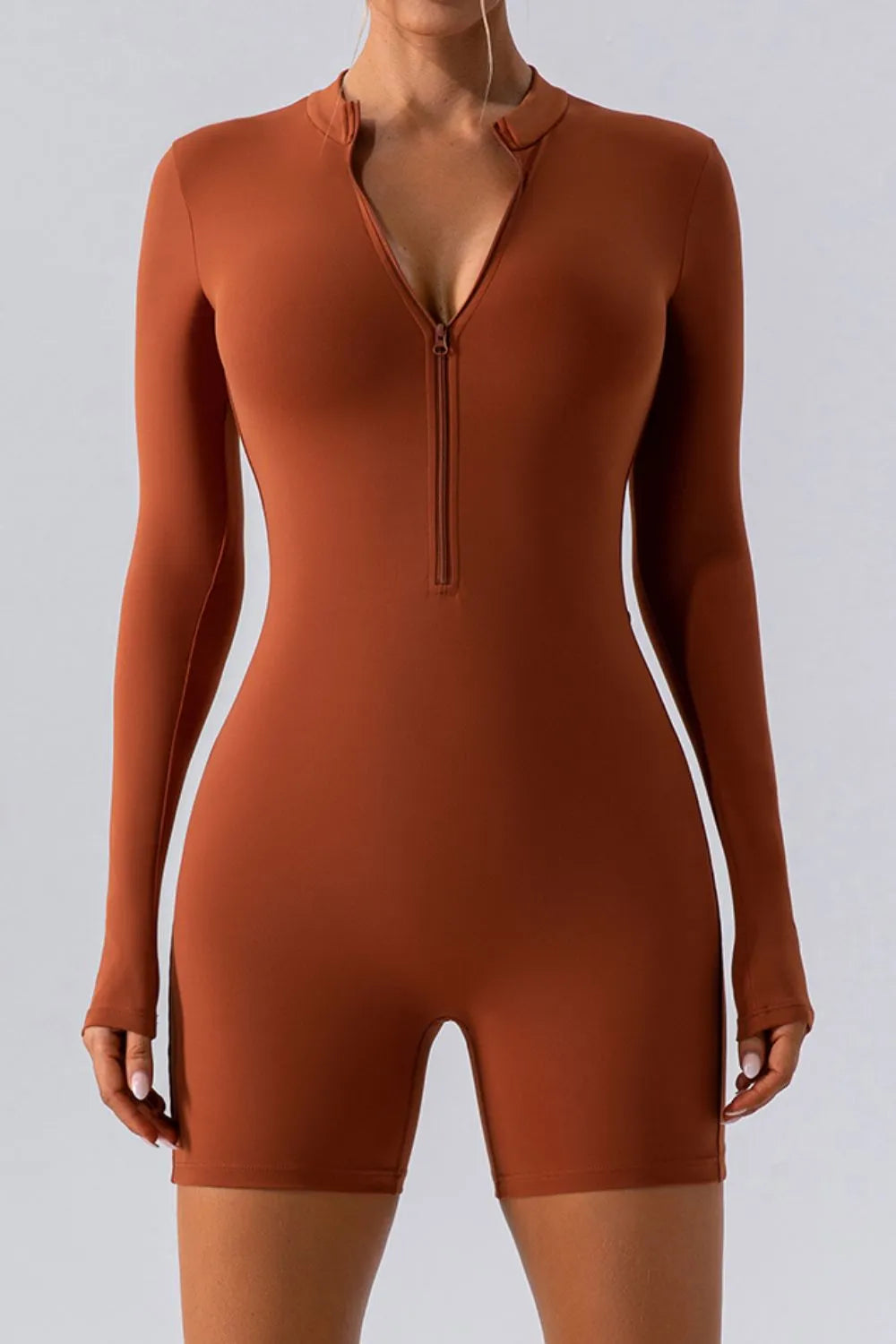 Model in a terracotta long sleeve romper, short legs, front zip open to a deep V