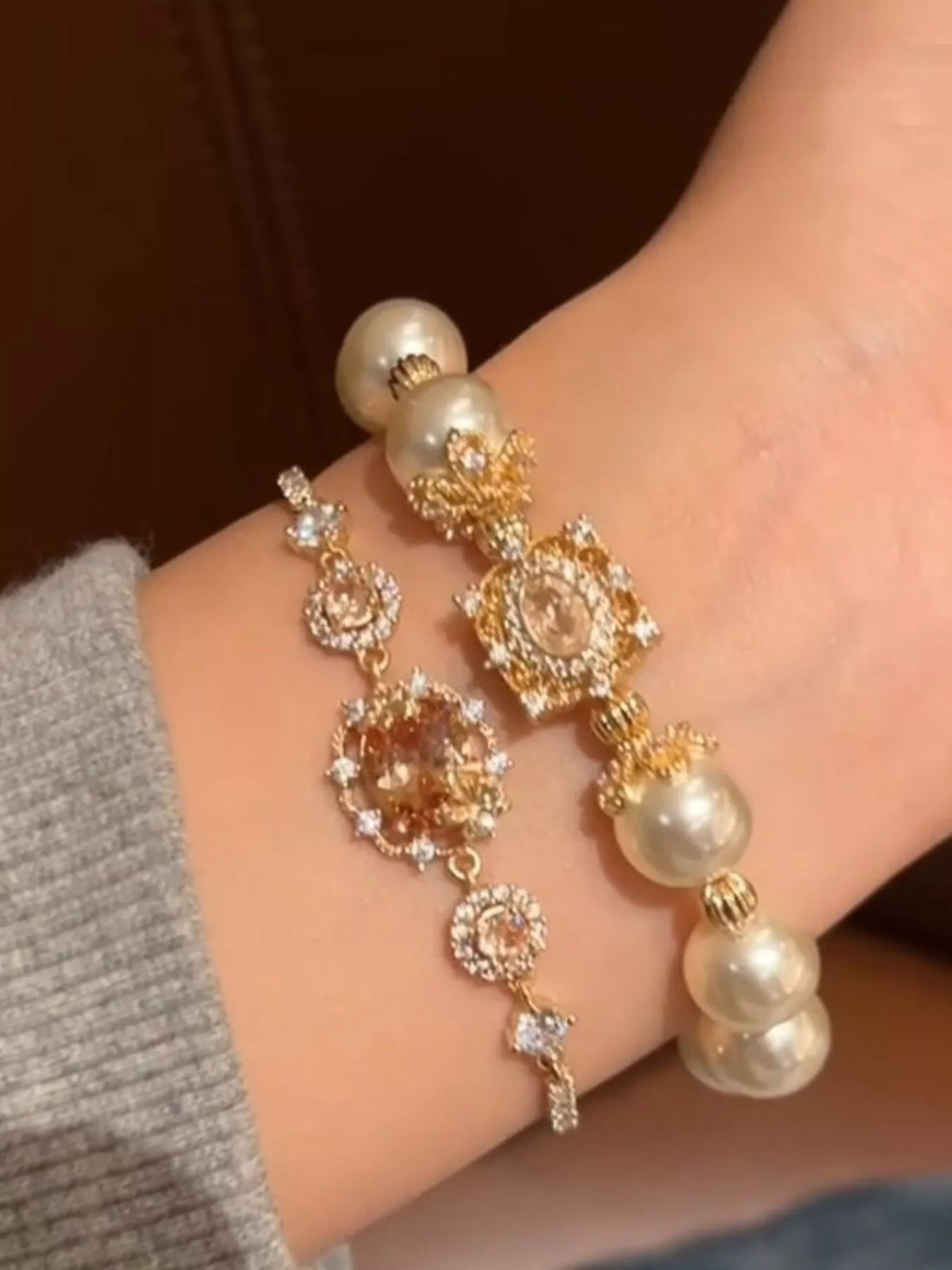 Close-up of a hand wearing a decorative bracelet with pearls and gold accents.
