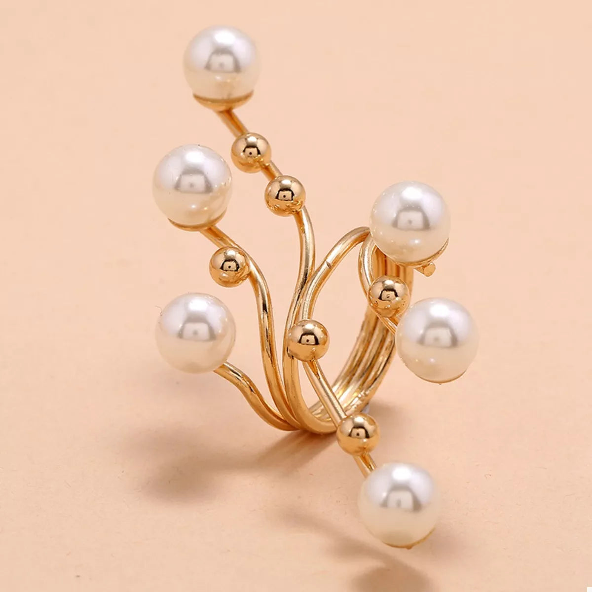 Gold ring with pearl beads on a beige background