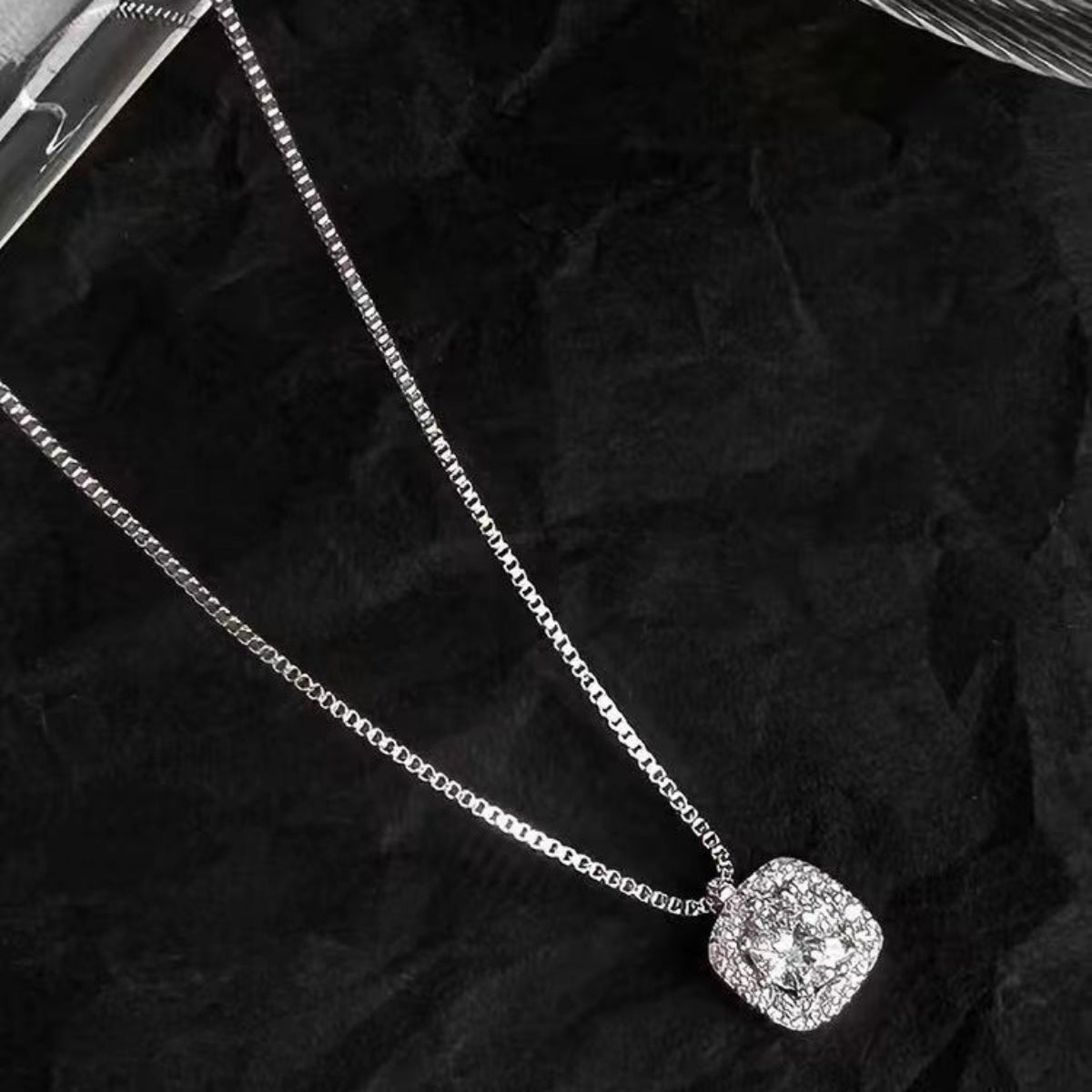 Flat lay of square pendant necklace with matching luxury gift box