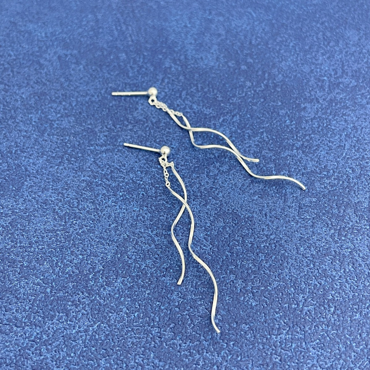 Side profile of 2" long wave earrings showing curved sterling silver shape