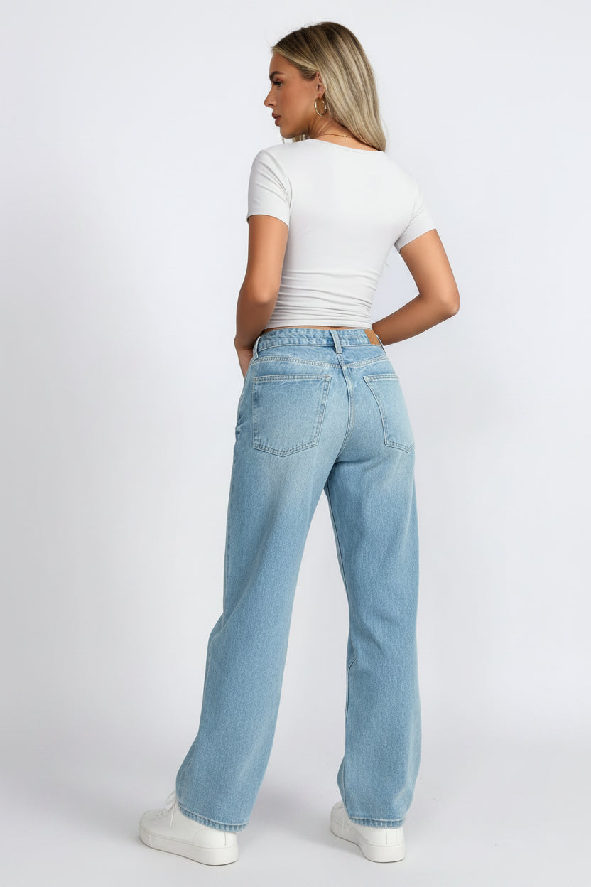 Person wearing a white t-shirt and light blue jeans on a plain background