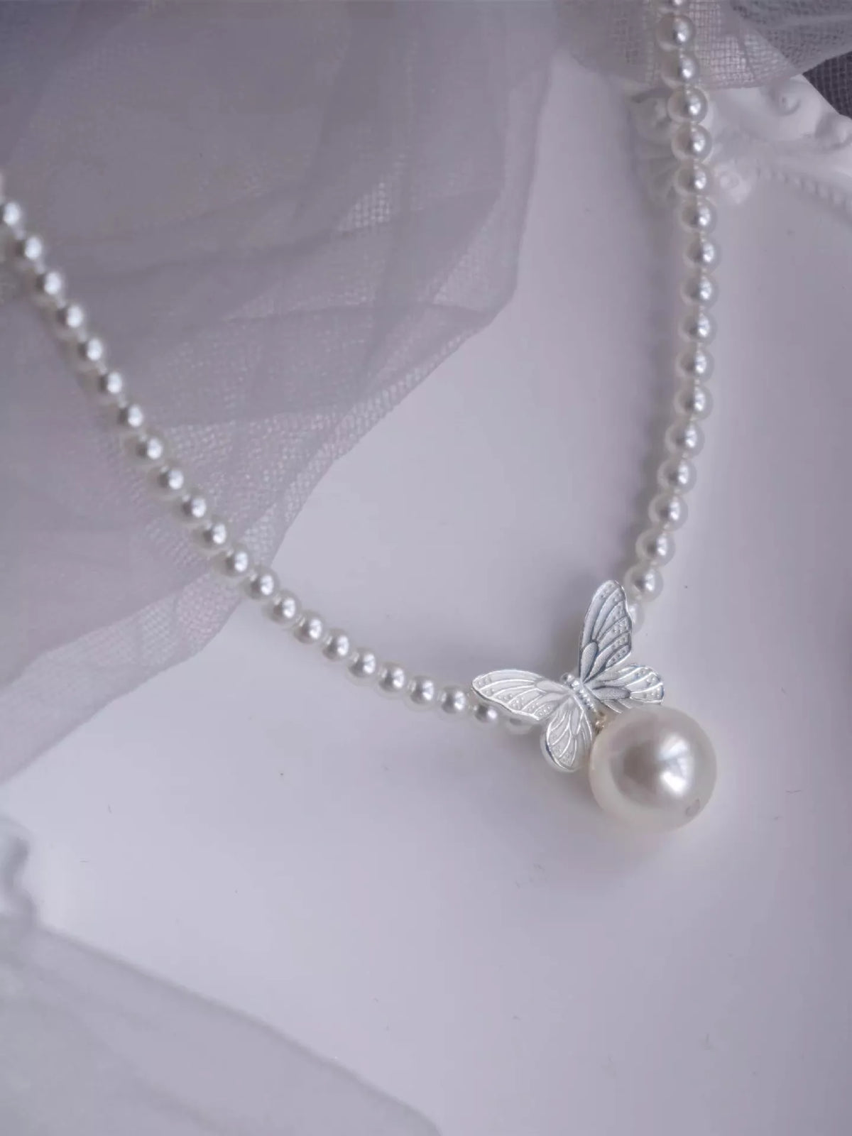 Pearl necklace with a butterfly pendant on a white background