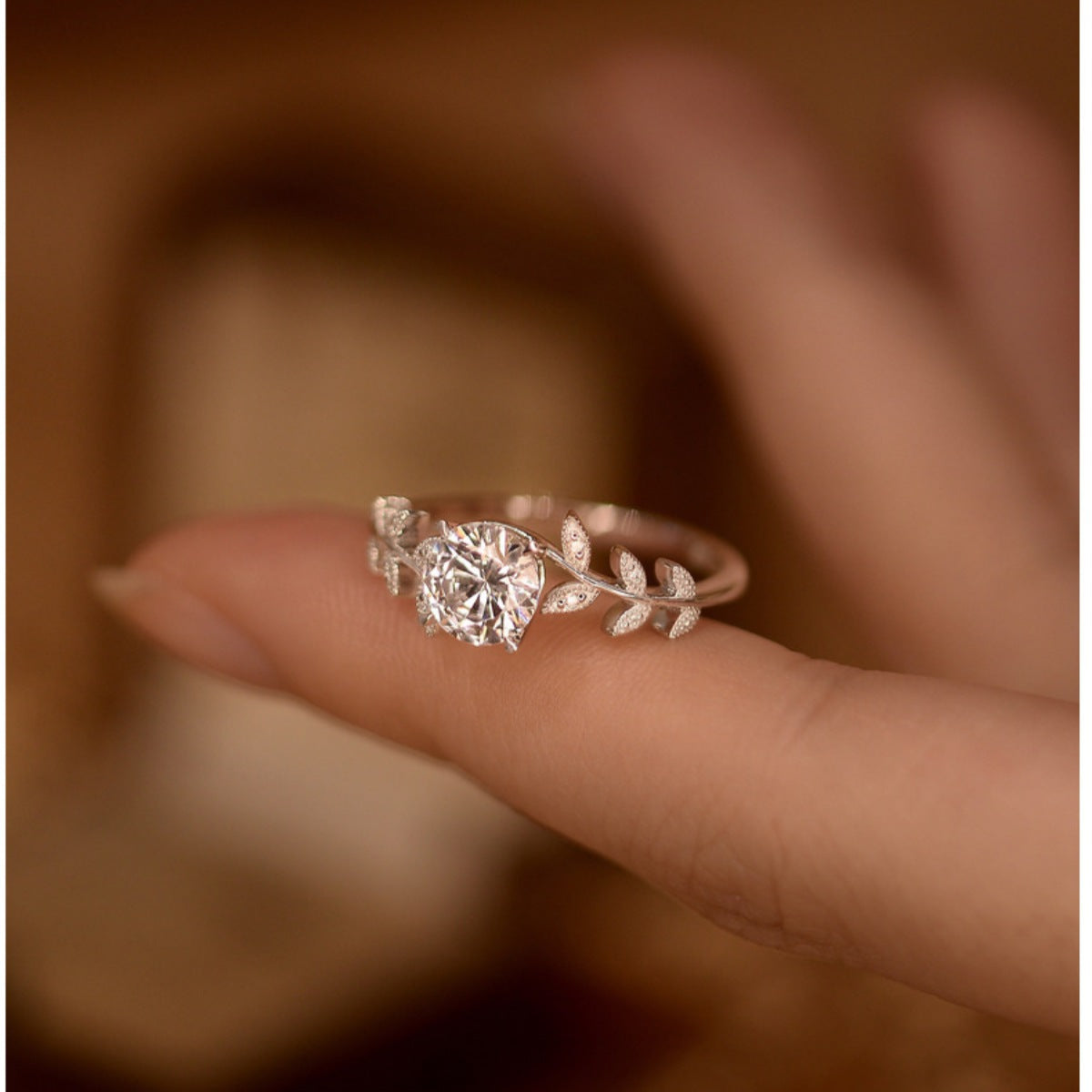 Rose gold ring with a diamond on a finger against a blurred background