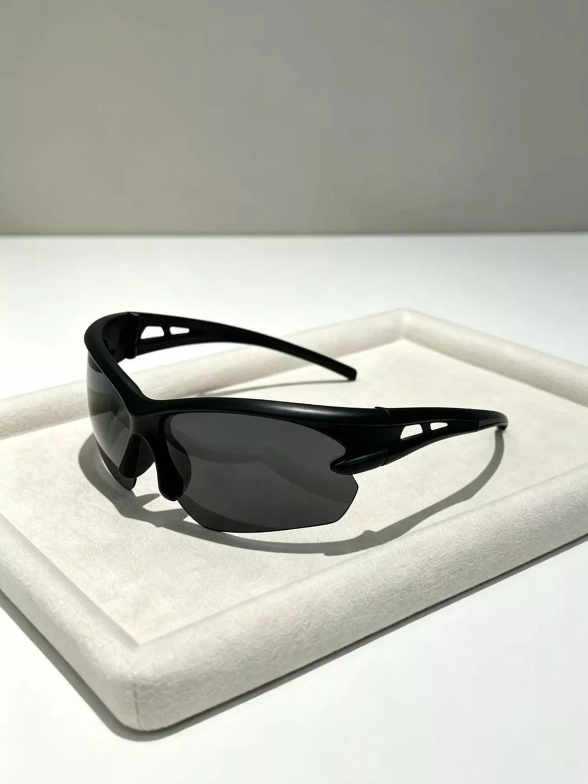 Black sunglasses on a white cushion with a neutral background