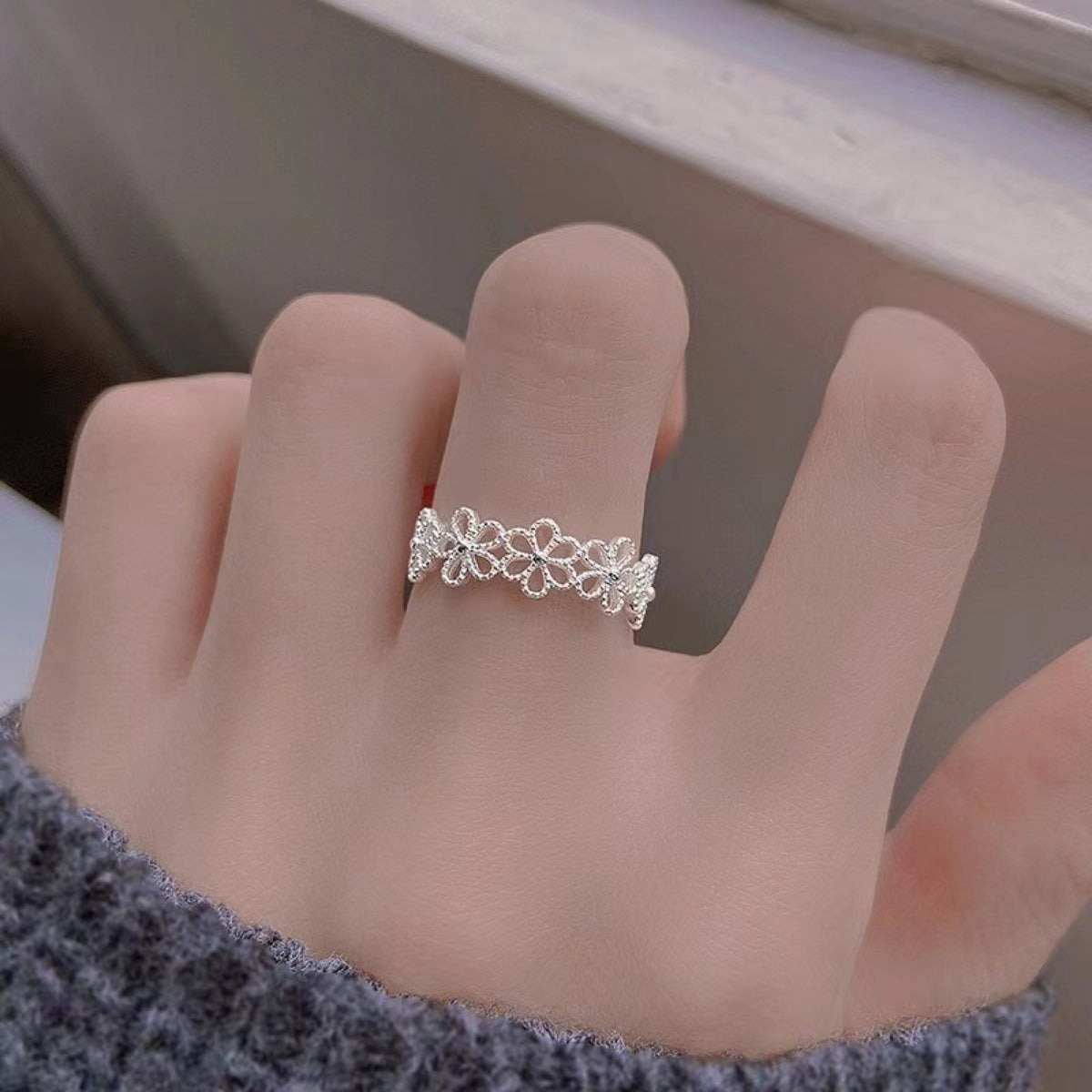 Model stacking the floral ring with other silver rings for bold hand styling