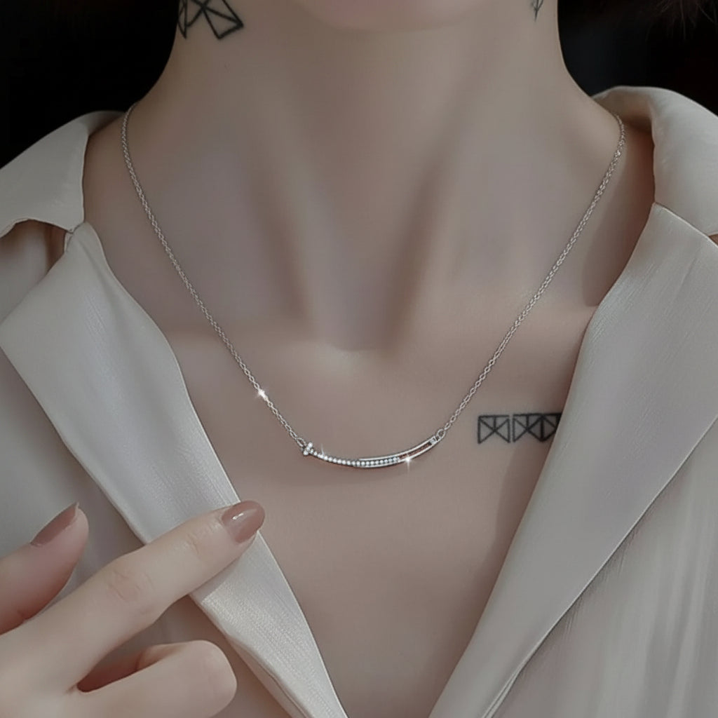 Silver necklace being worn on a person with a neutral background