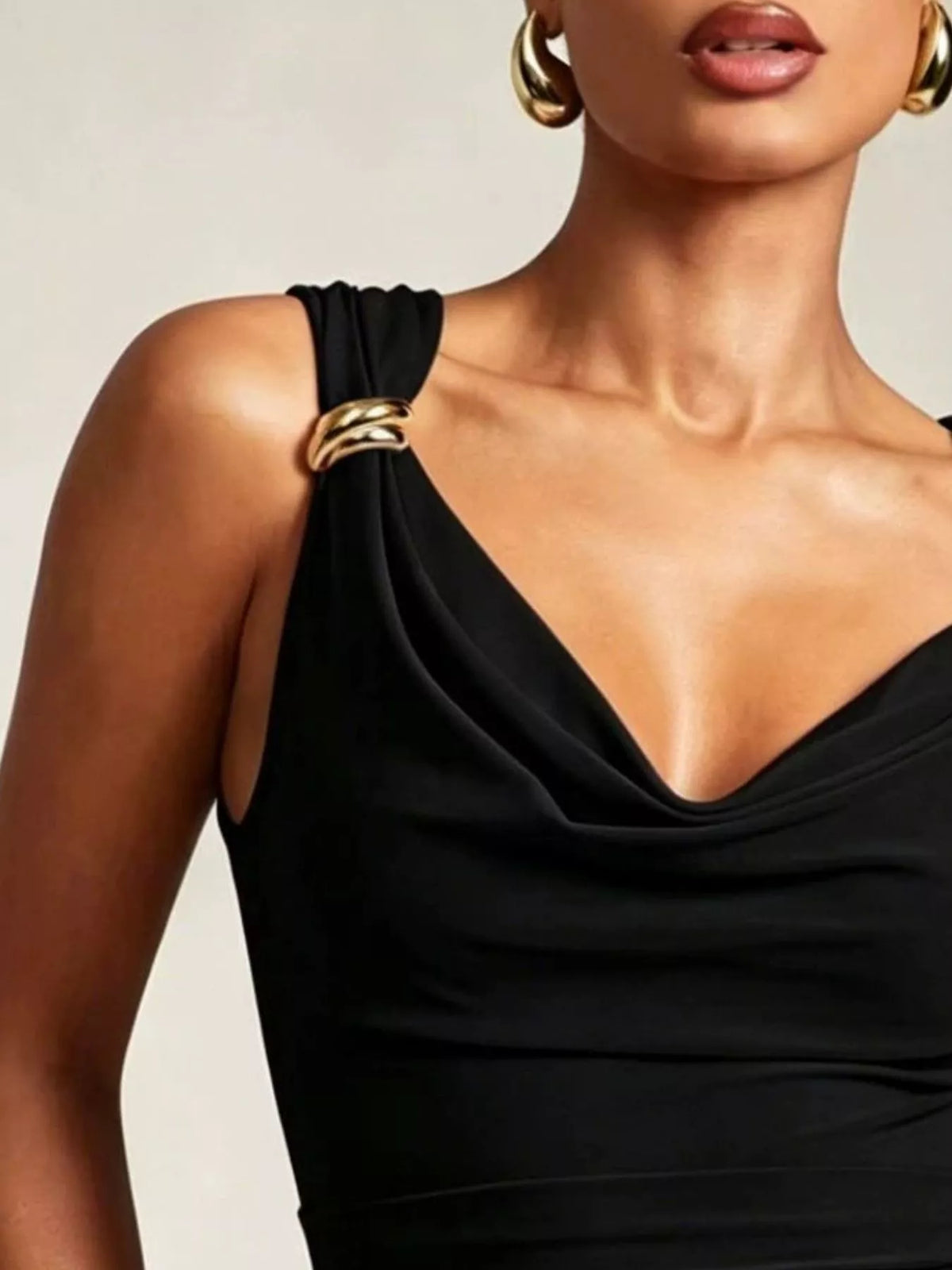 Black one-shoulder dress with gold accents worn by a model against a neutral background