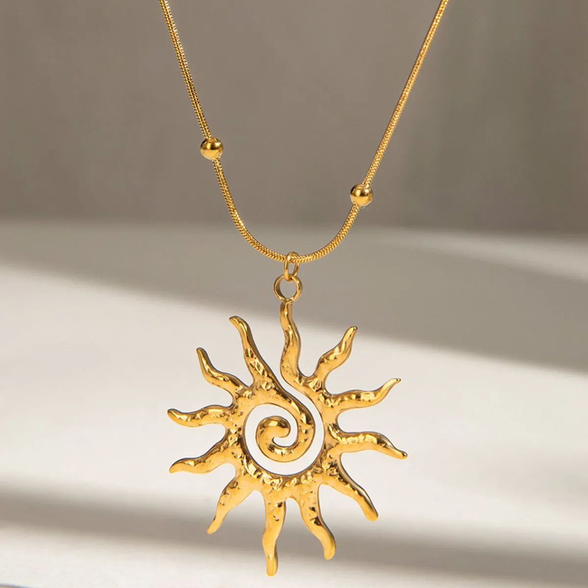 sun pendant necklace close up shot with a neutral tone background