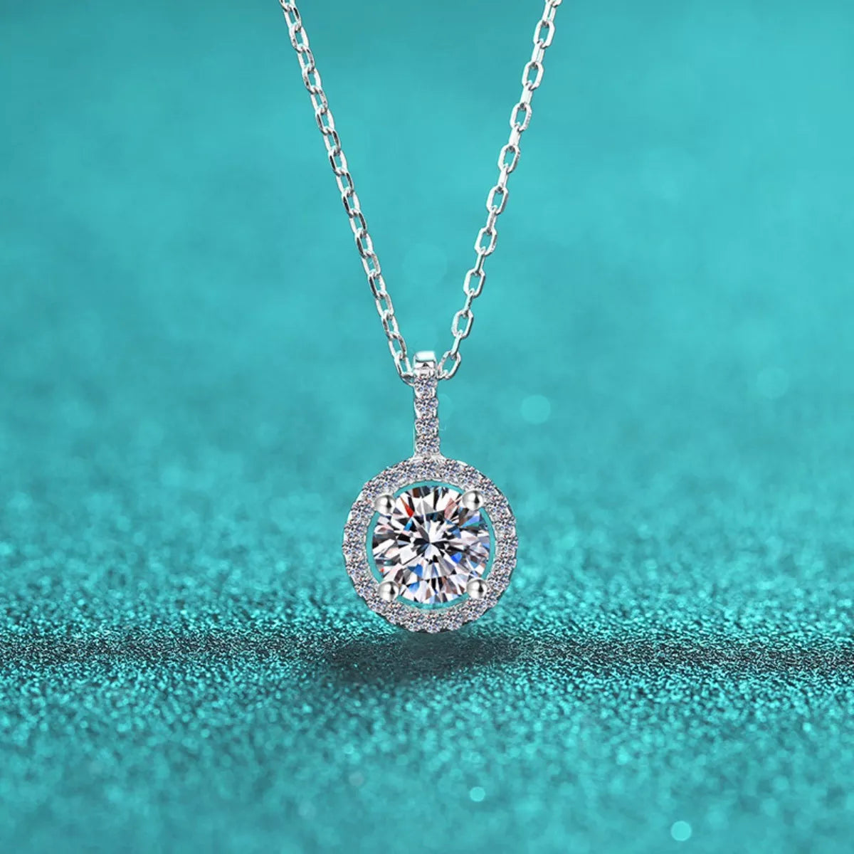 Silver necklace with a round diamond pendant on a teal background