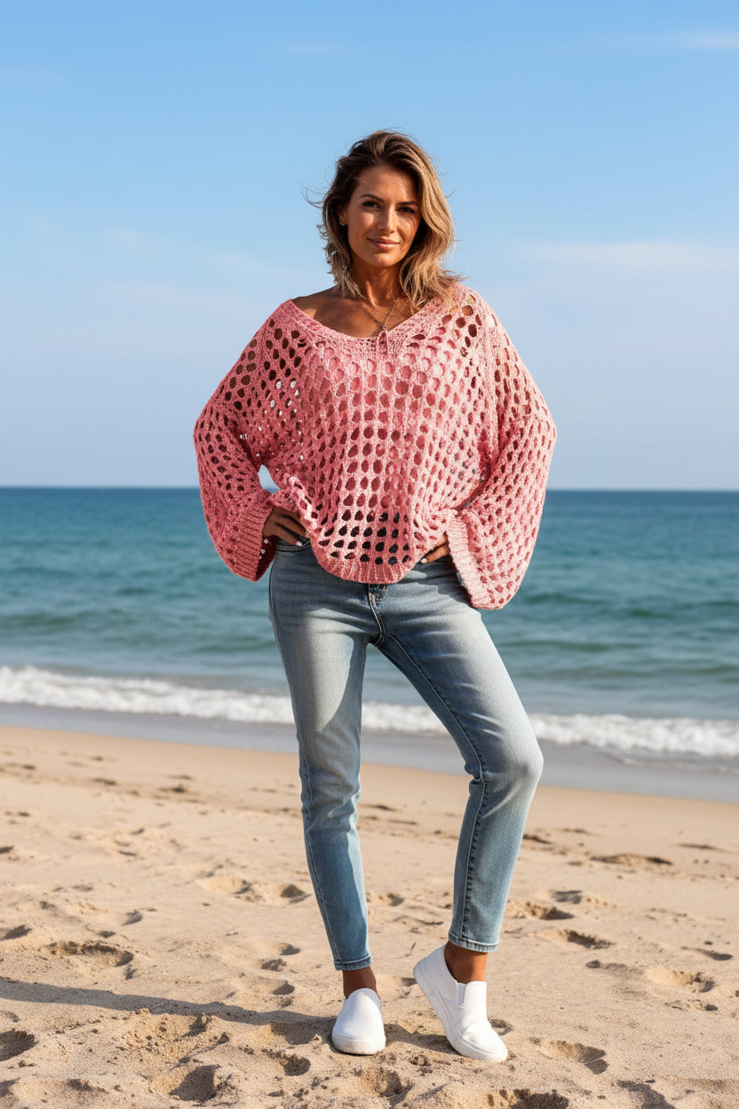 Person wearing a pink crochet sweater with a blurred background