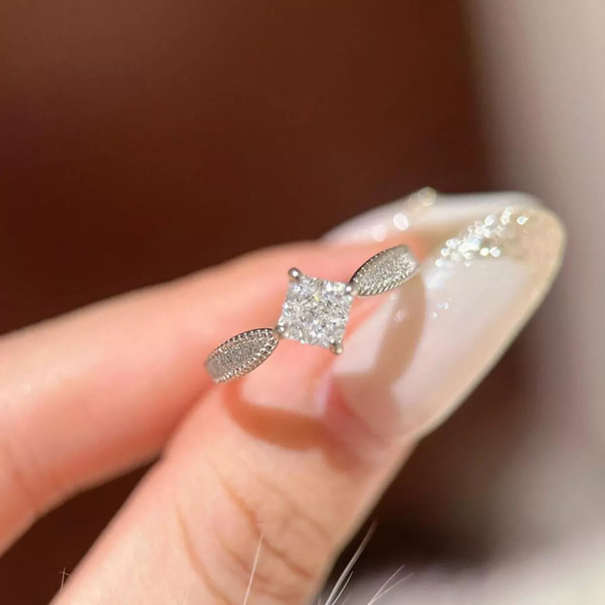 Silver earring being worn on a finger with a blurred background