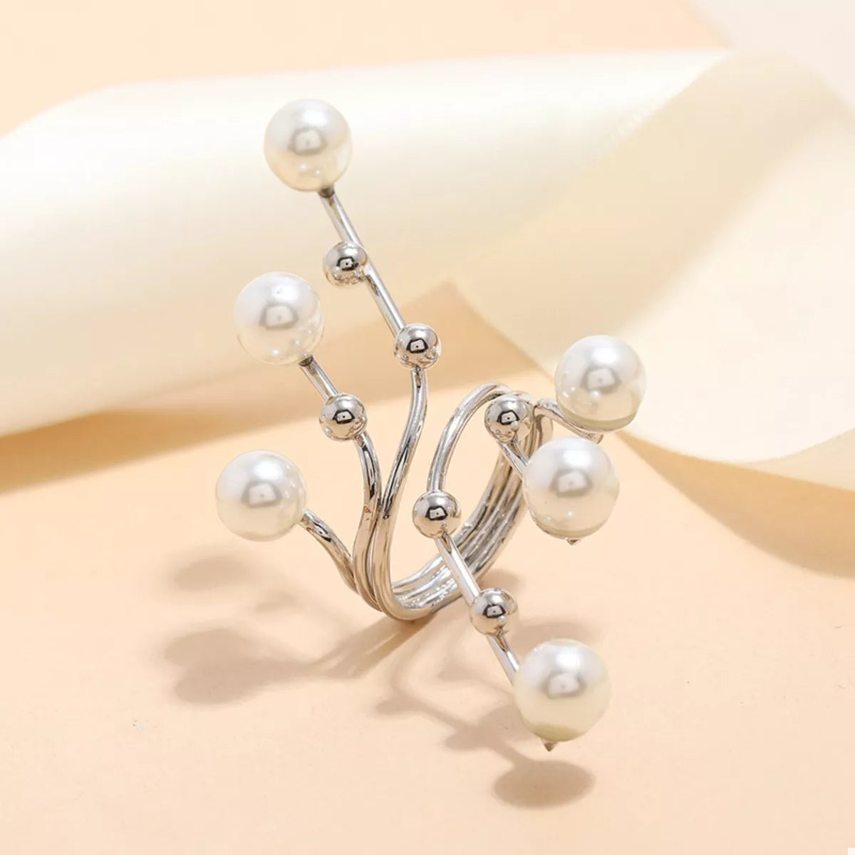 Silver ring with pearls on a beige background