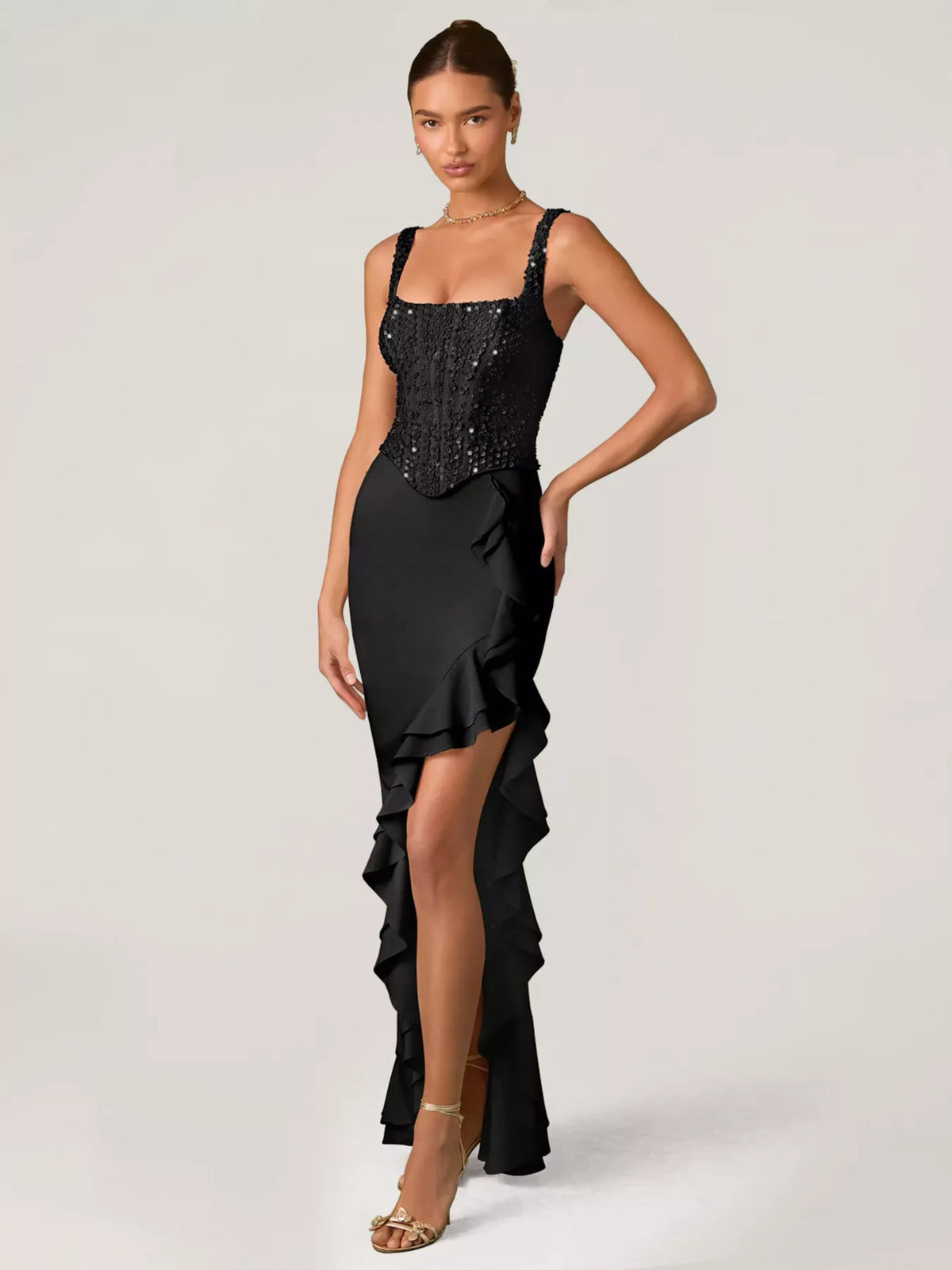 Woman wearing a black evening gown with sequin detailing on a white background
