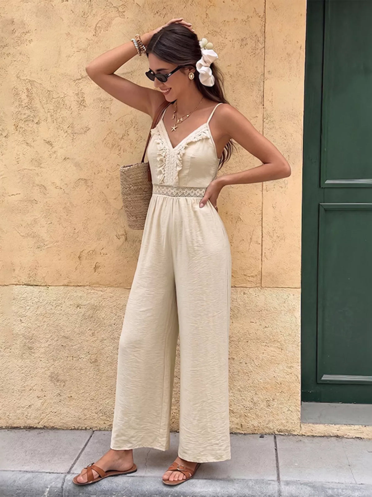 Woman in a white dress standing against a beige wall with a green door.