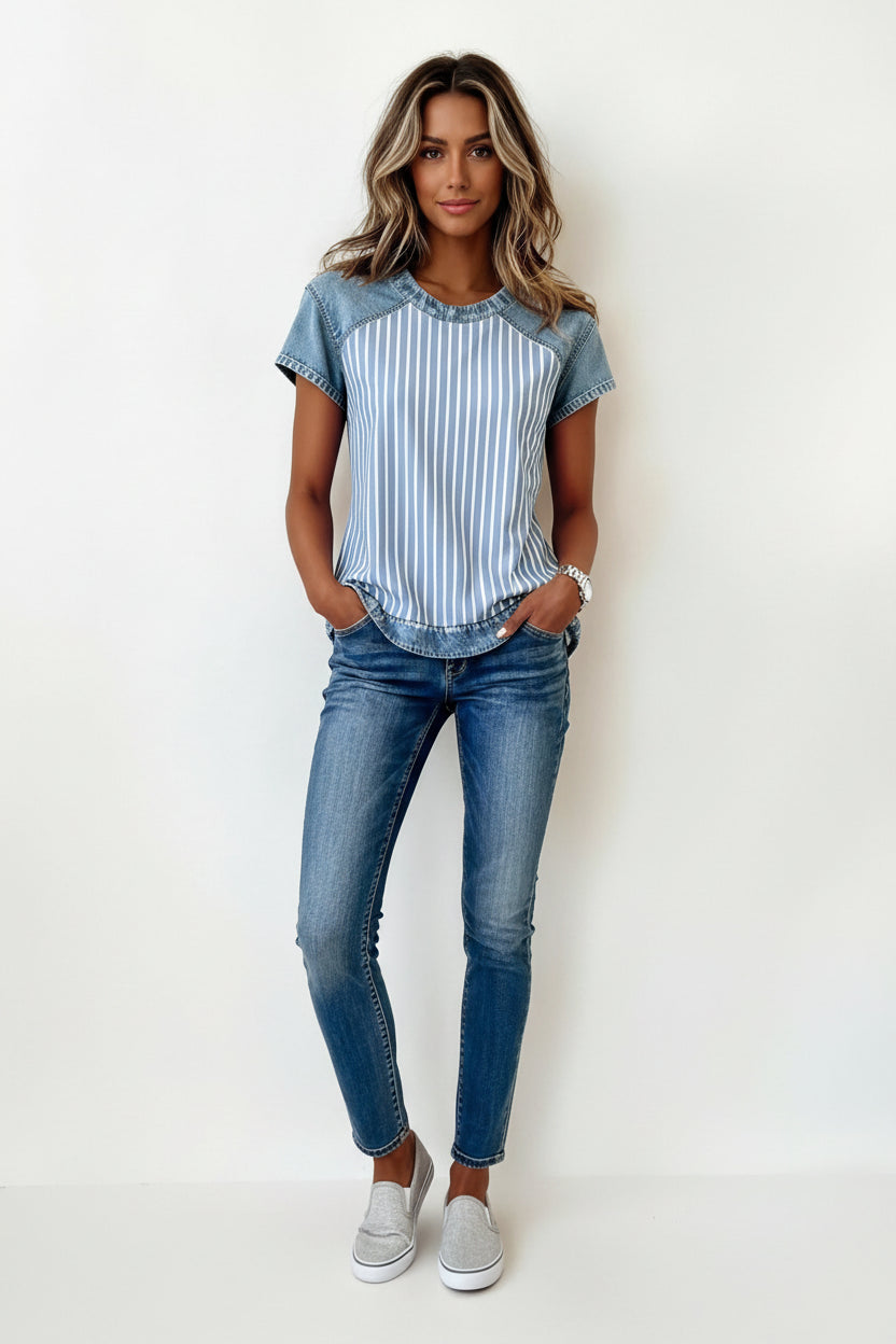 Woman wearing a blue and white striped shirt with denim sleeves against a plain background