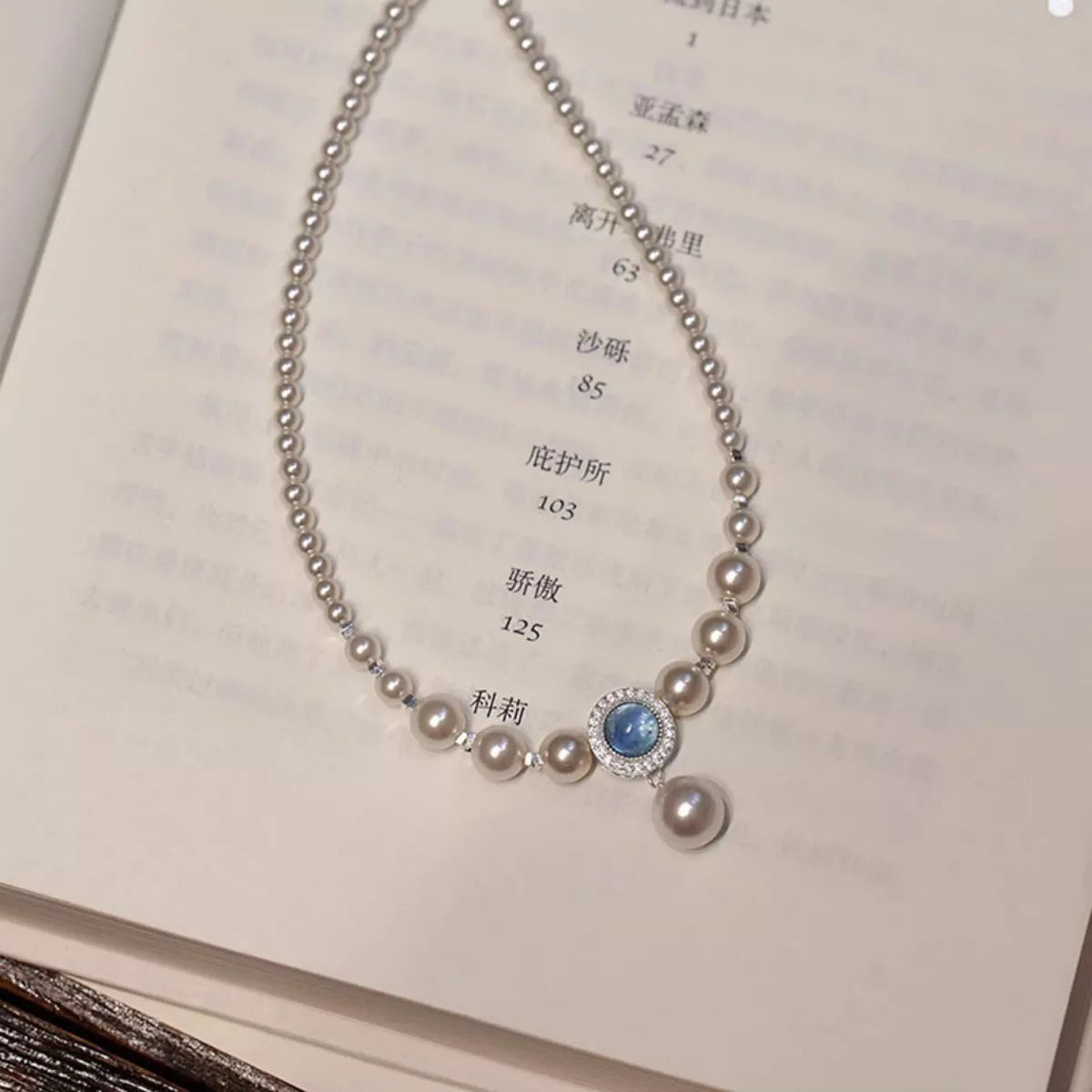 Close-up of luminous synthetic pearl and natural stone accent on sterling silver chain