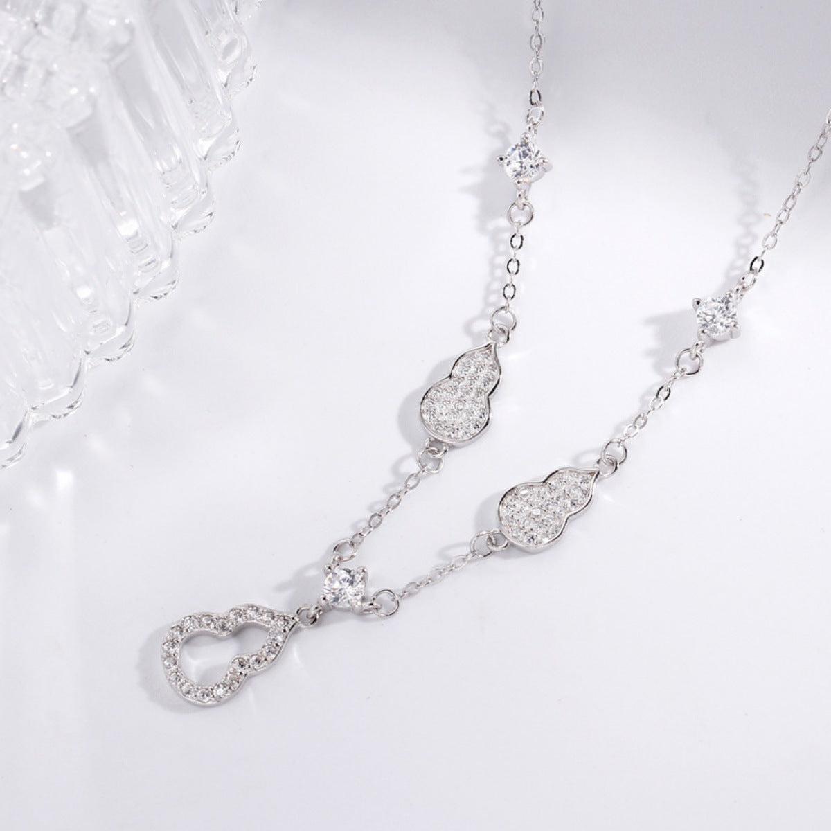 Silver necklace with heart-shaped links on a light gray background