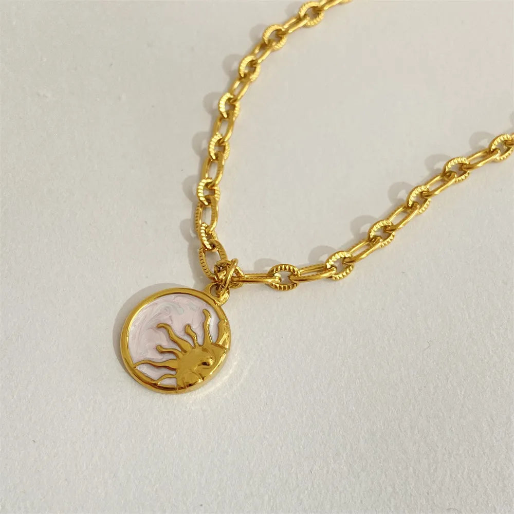 Gold chain bracelet with a round pendant on a light gray background