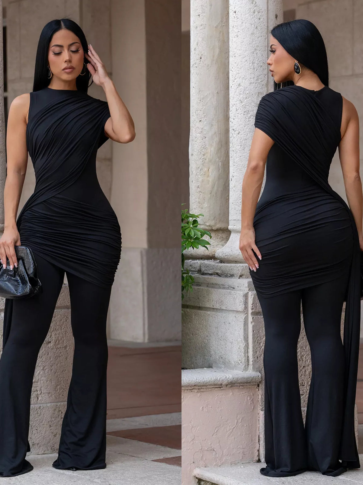 Woman in a black dress posing against a stone wall.