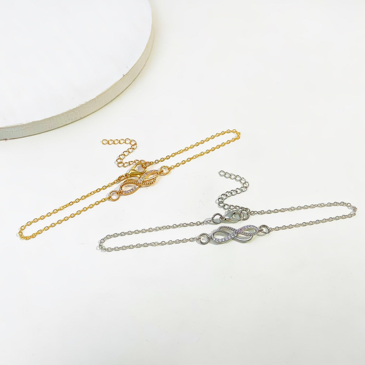 Flat lay of infinity knot charm bracelet with matching luxury gift box