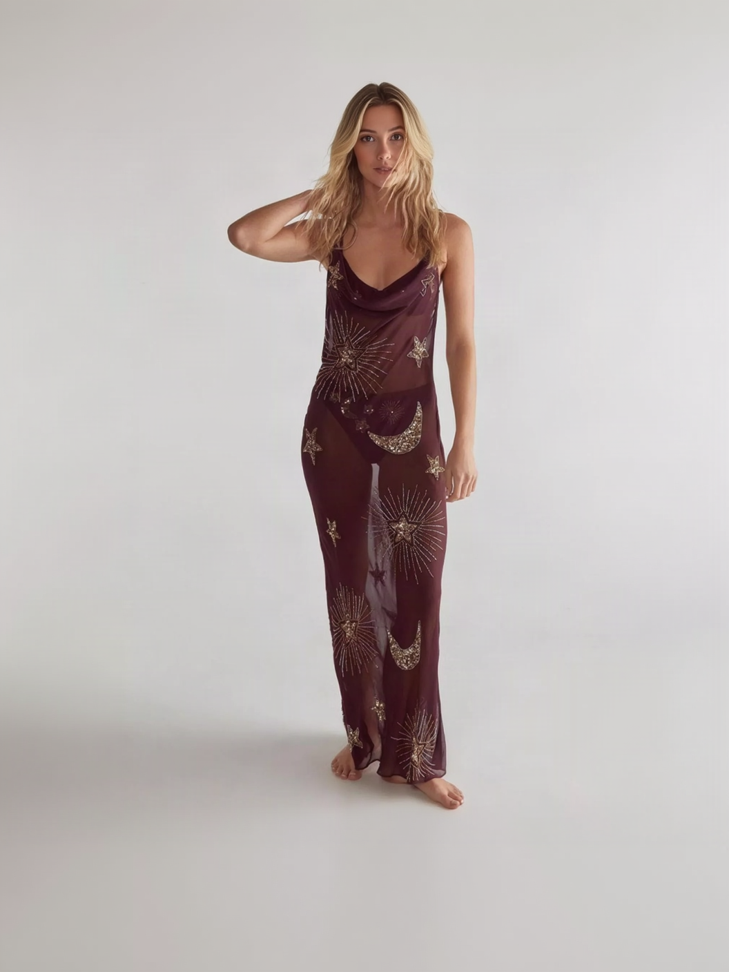 Sheer burgundy maxi dress with gold star and moon embroidery, barefoot, hand in hair