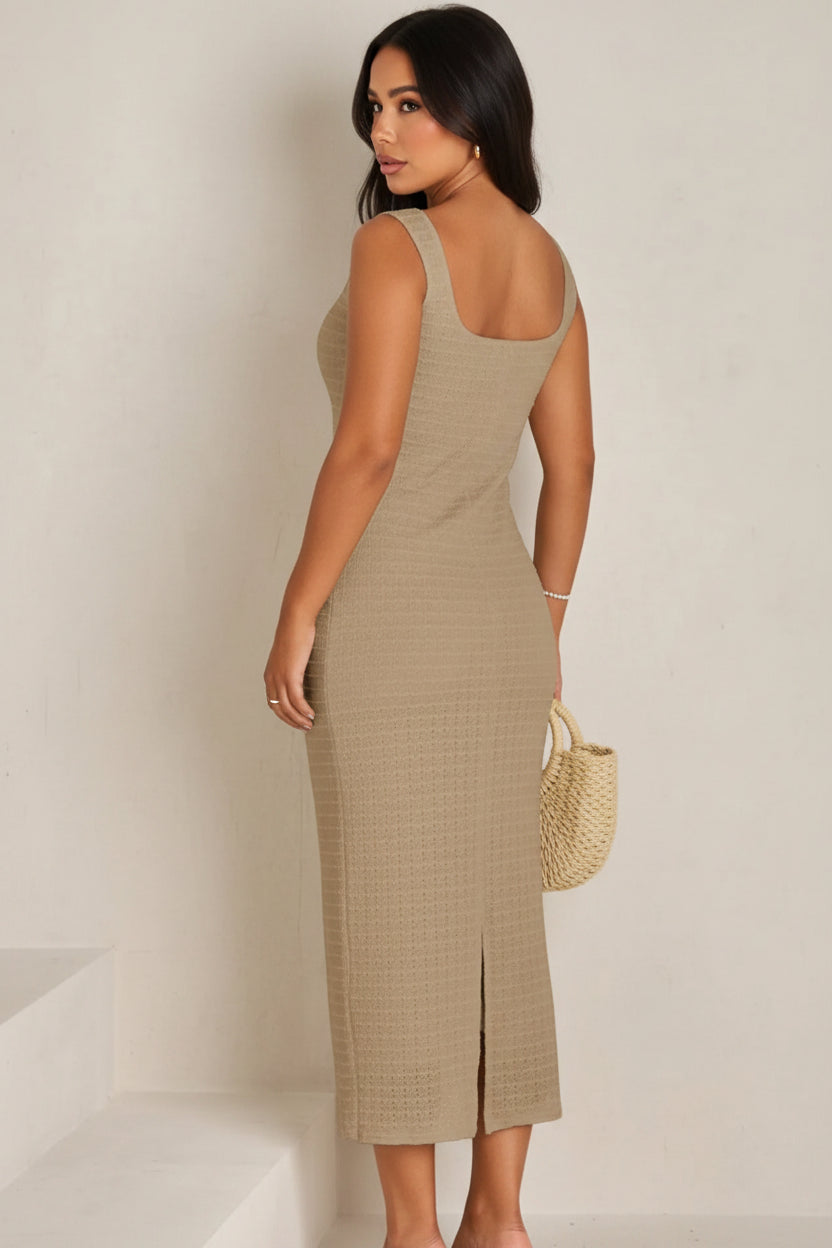Woman wearing a beige dress holding a woven bag against a white background