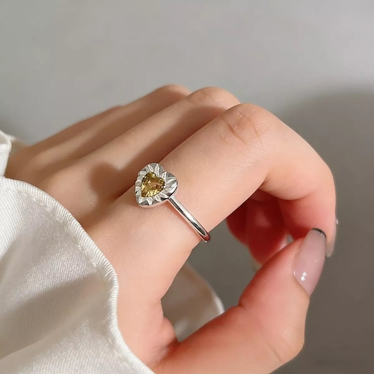 Model stacking the heart ring with other silver rings for bold hand styling