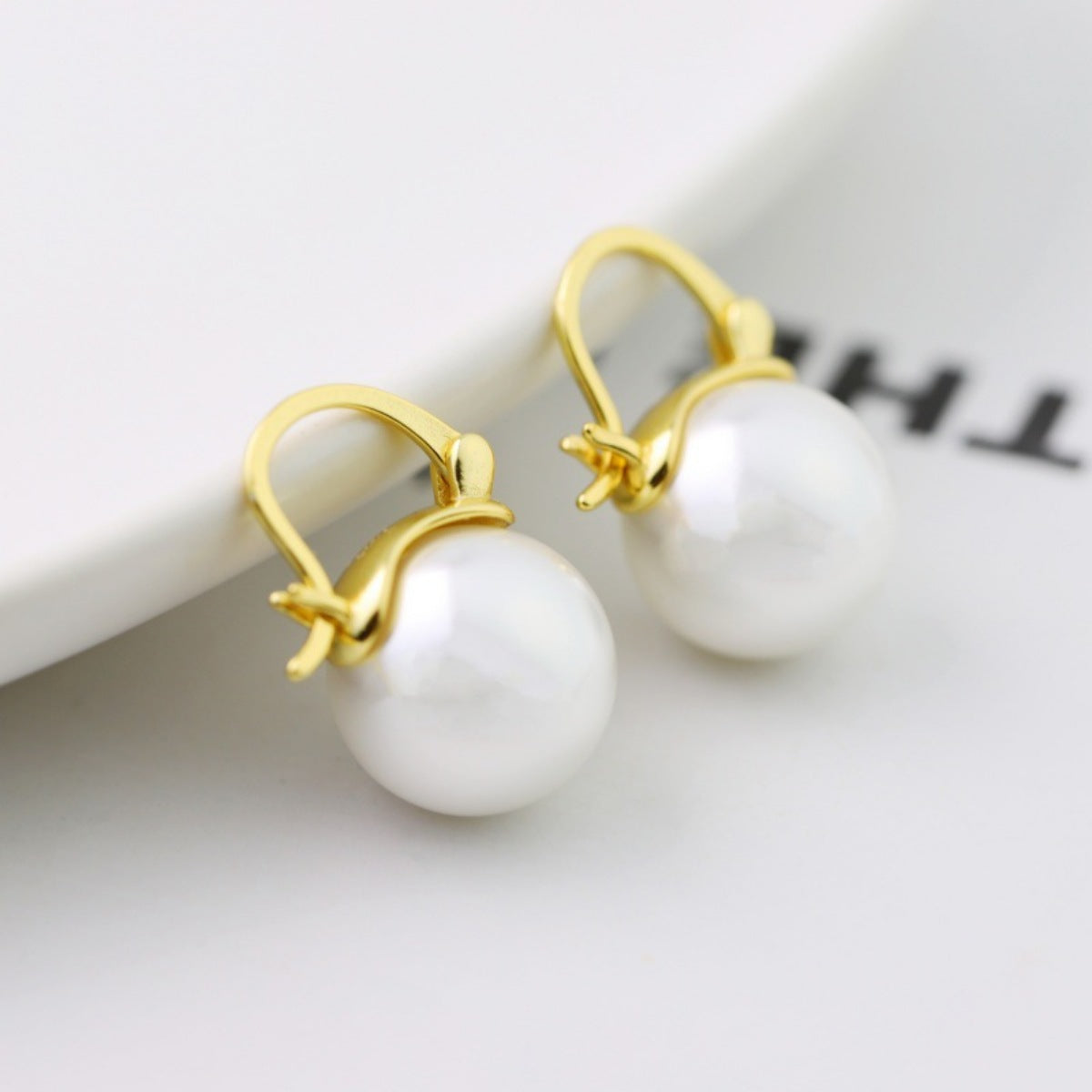 Close-up of luminous synthetic pearl on 18K gold-plated sterling silver earring