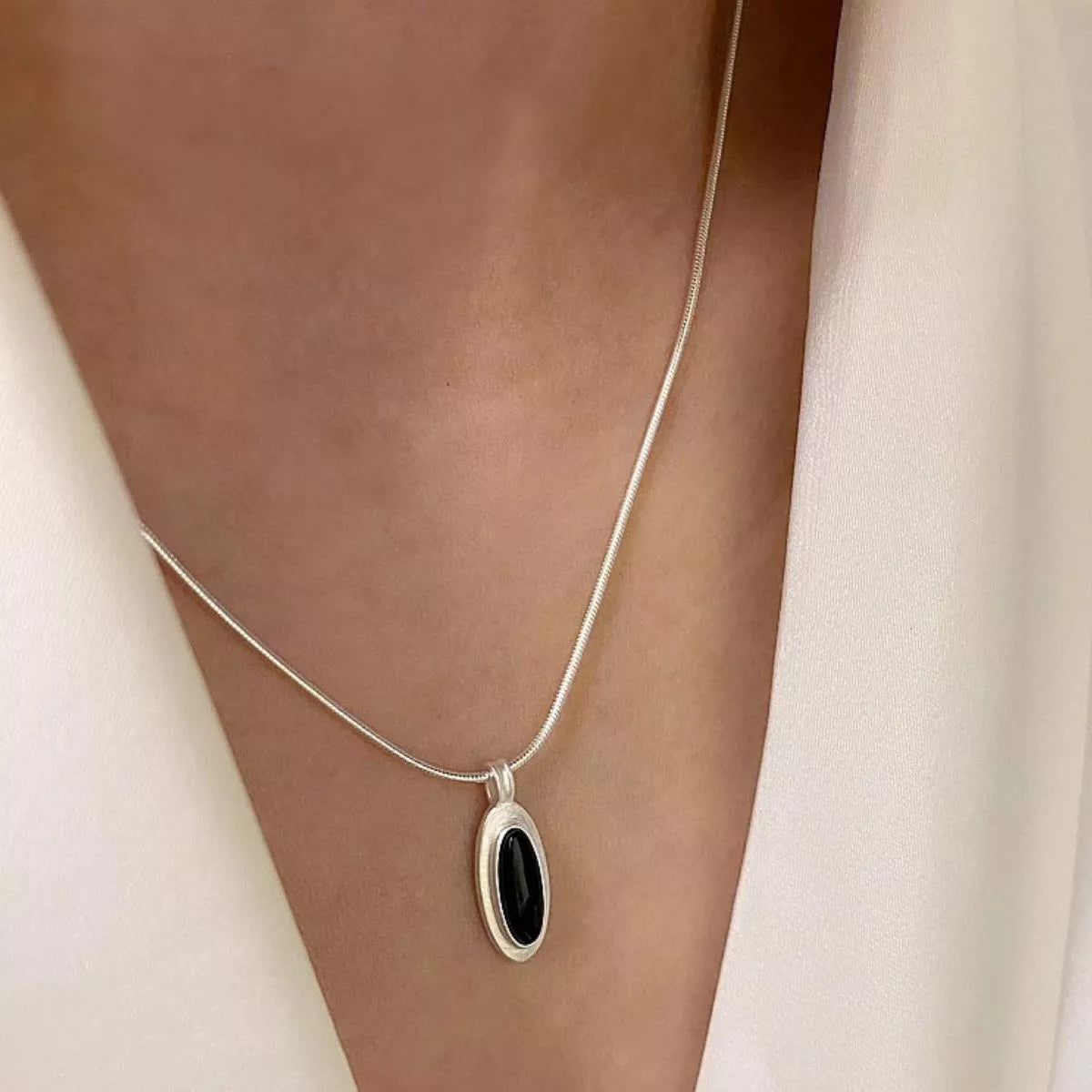 On-model close-up showing how the geometric pendant sits at the collarbone
