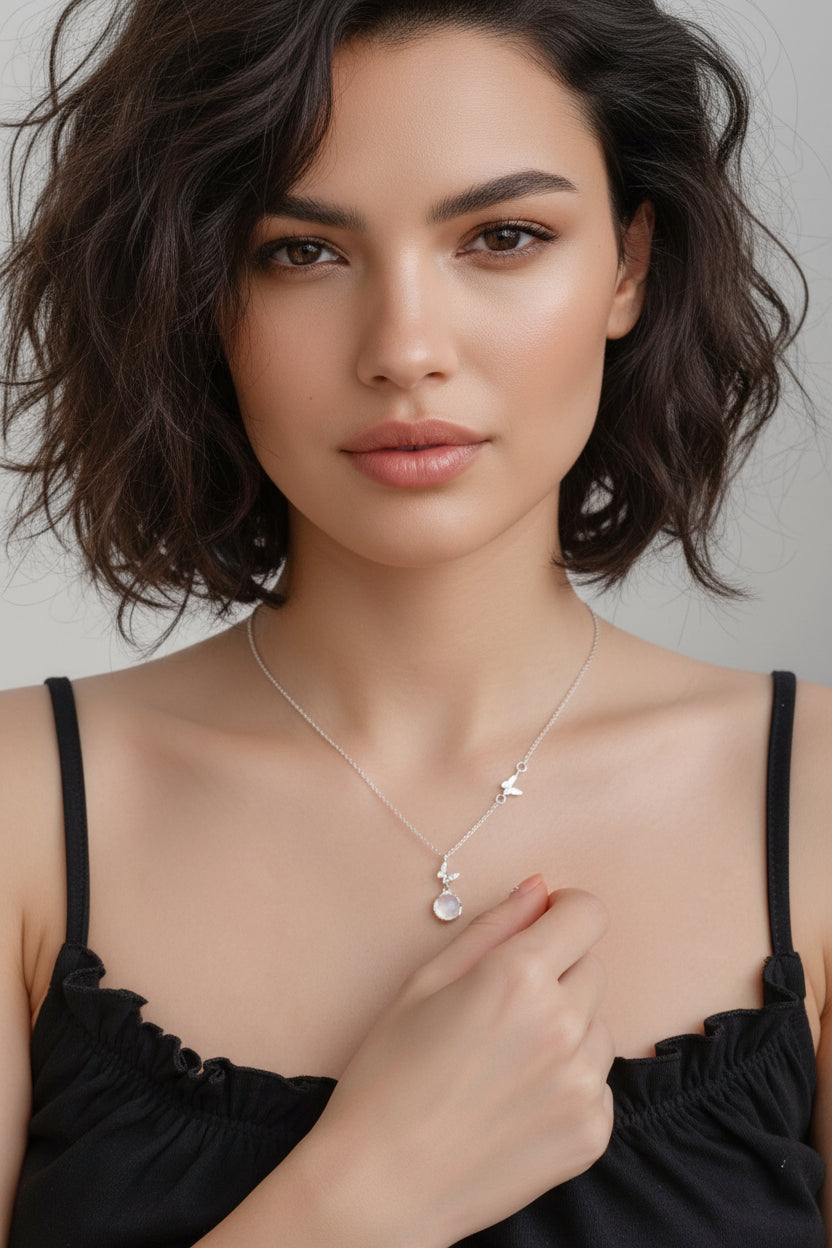 Person wearing a delicate silver necklace with a clear pendant