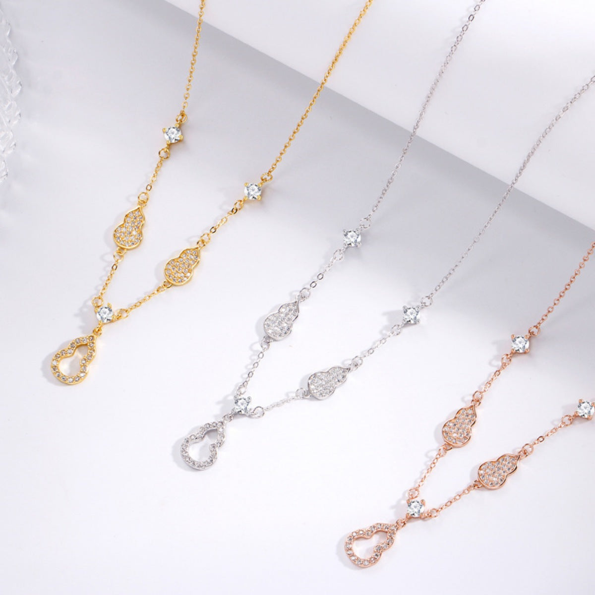 Three necklaces in gold, silver, and rose gold on a light gray background