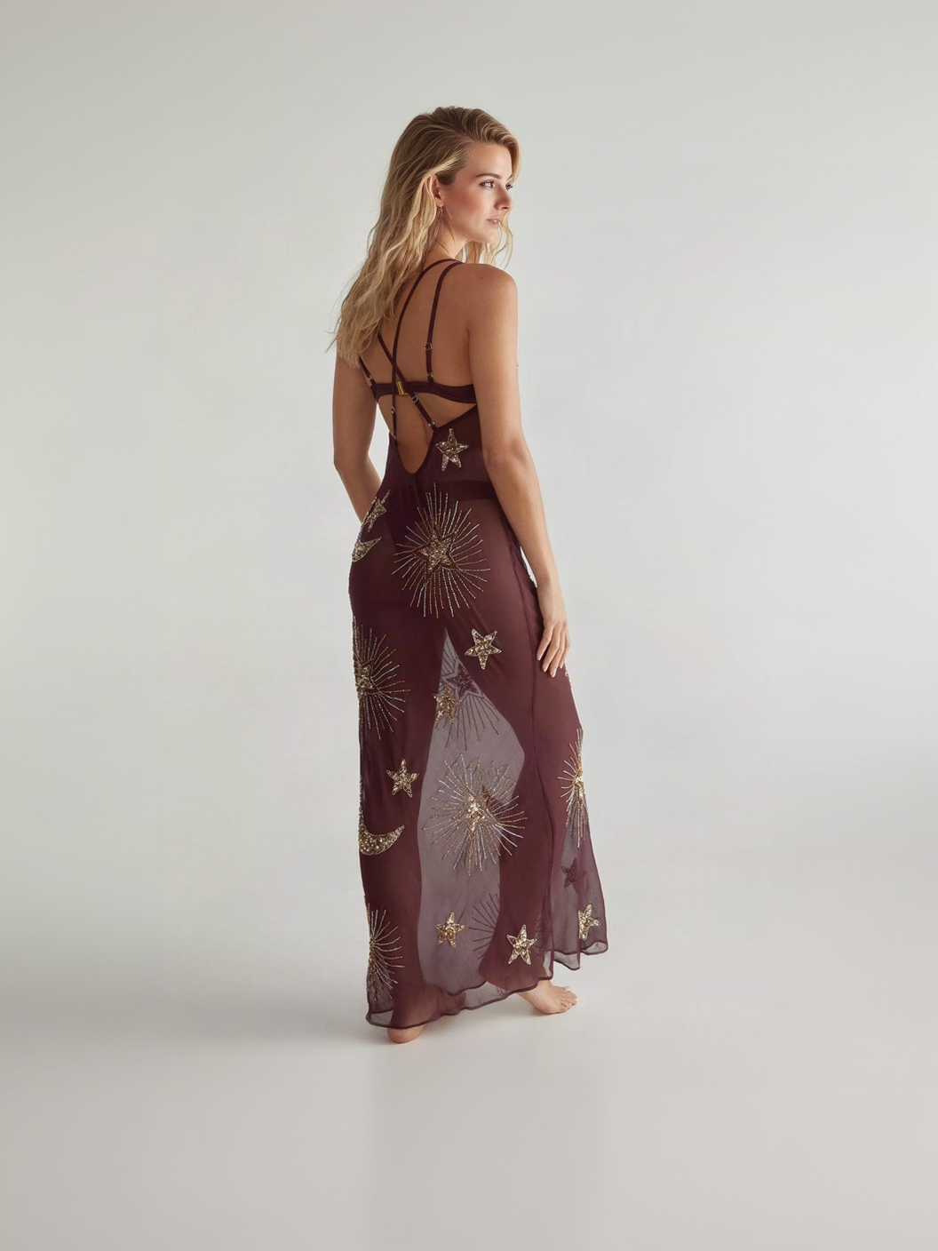 Back view of burgundy sheer maxi dress with crisscross straps and gold star embroidery