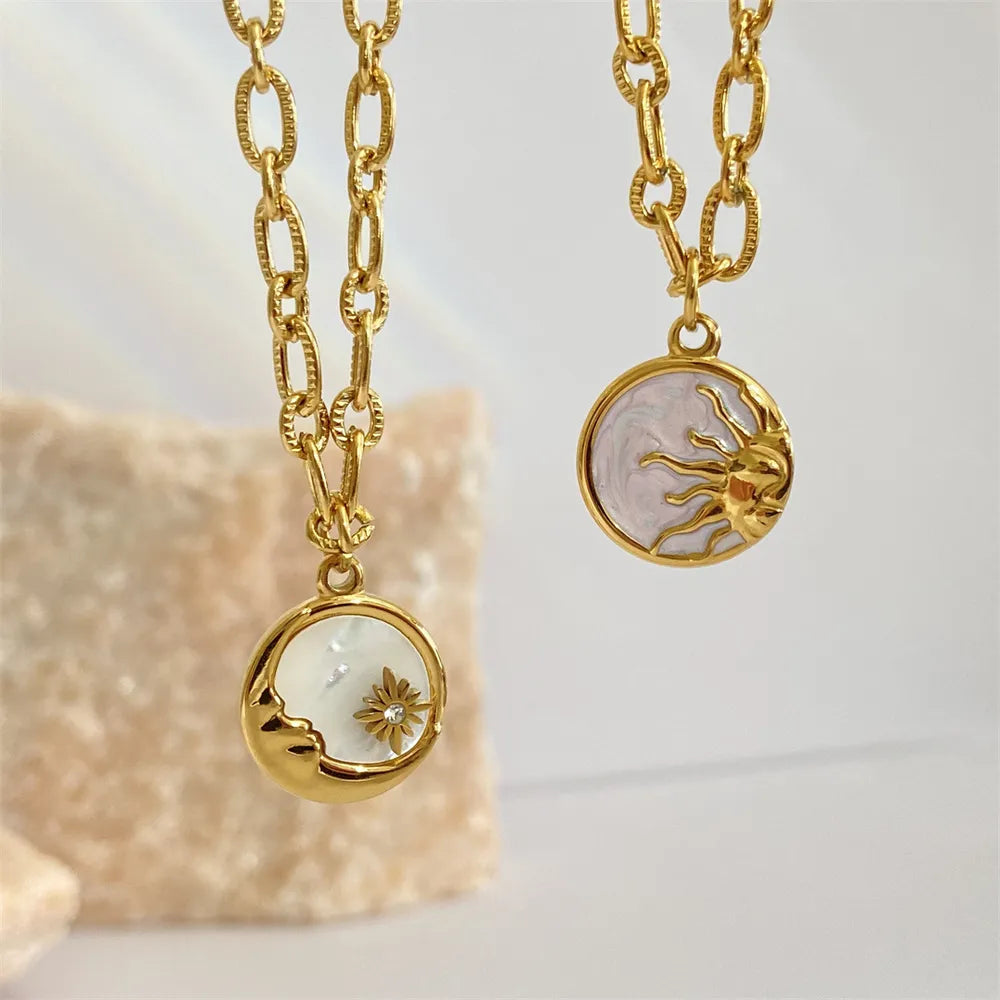 Two gold necklaces with circular pendants featuring floral designs on a light background.