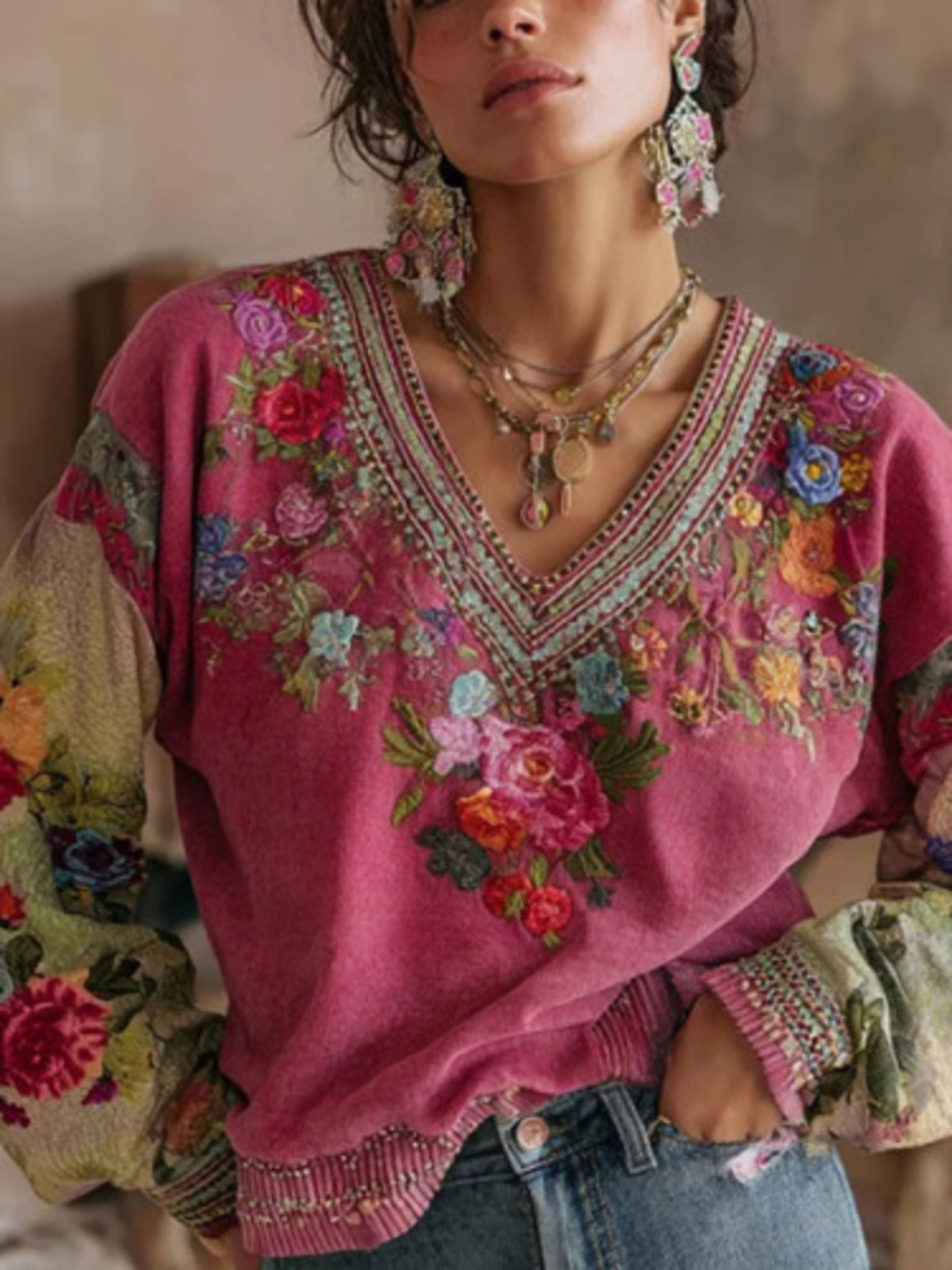 Woman wearing a pink embroidered sweater with colorful floral patterns.