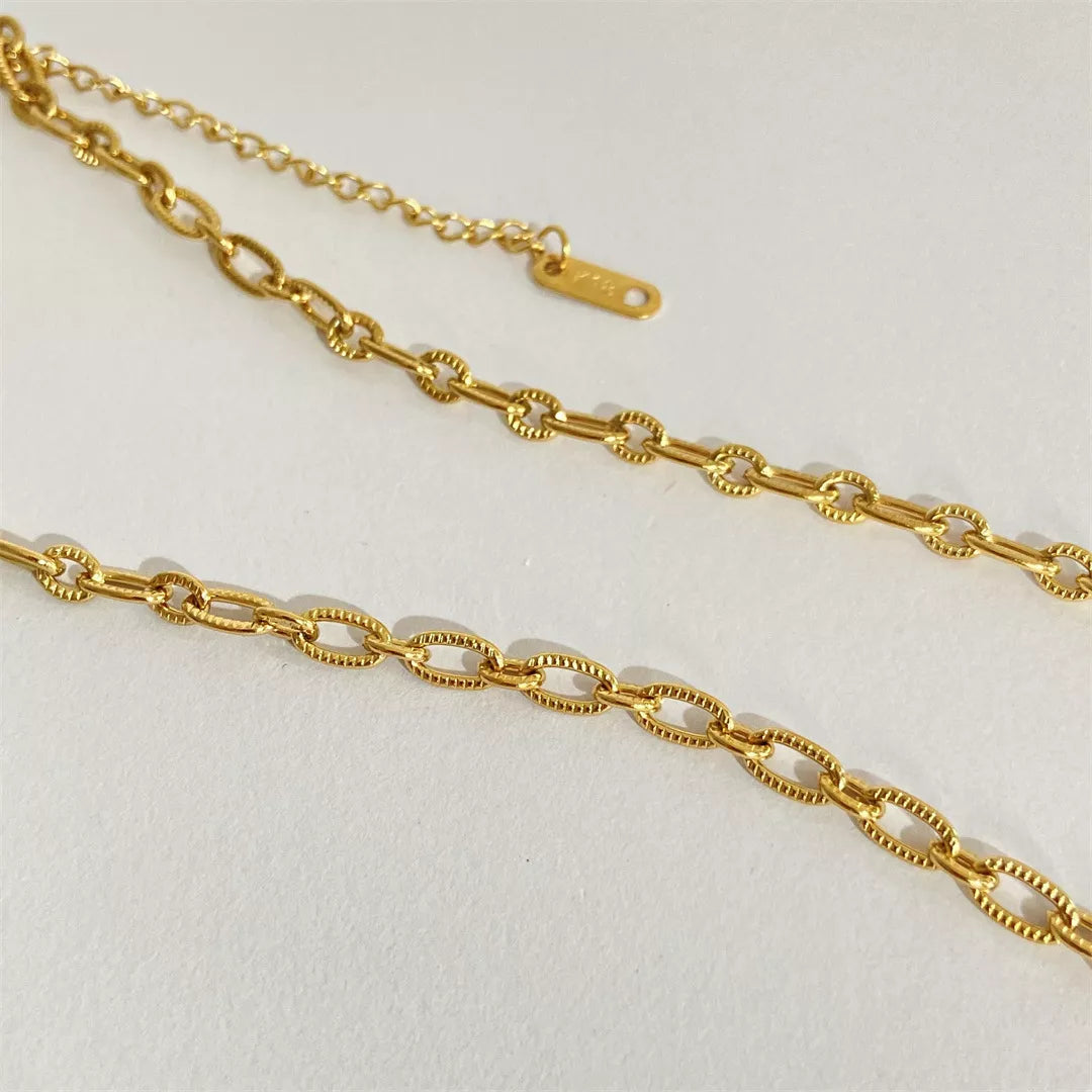 Gold chain necklace on a light gray background