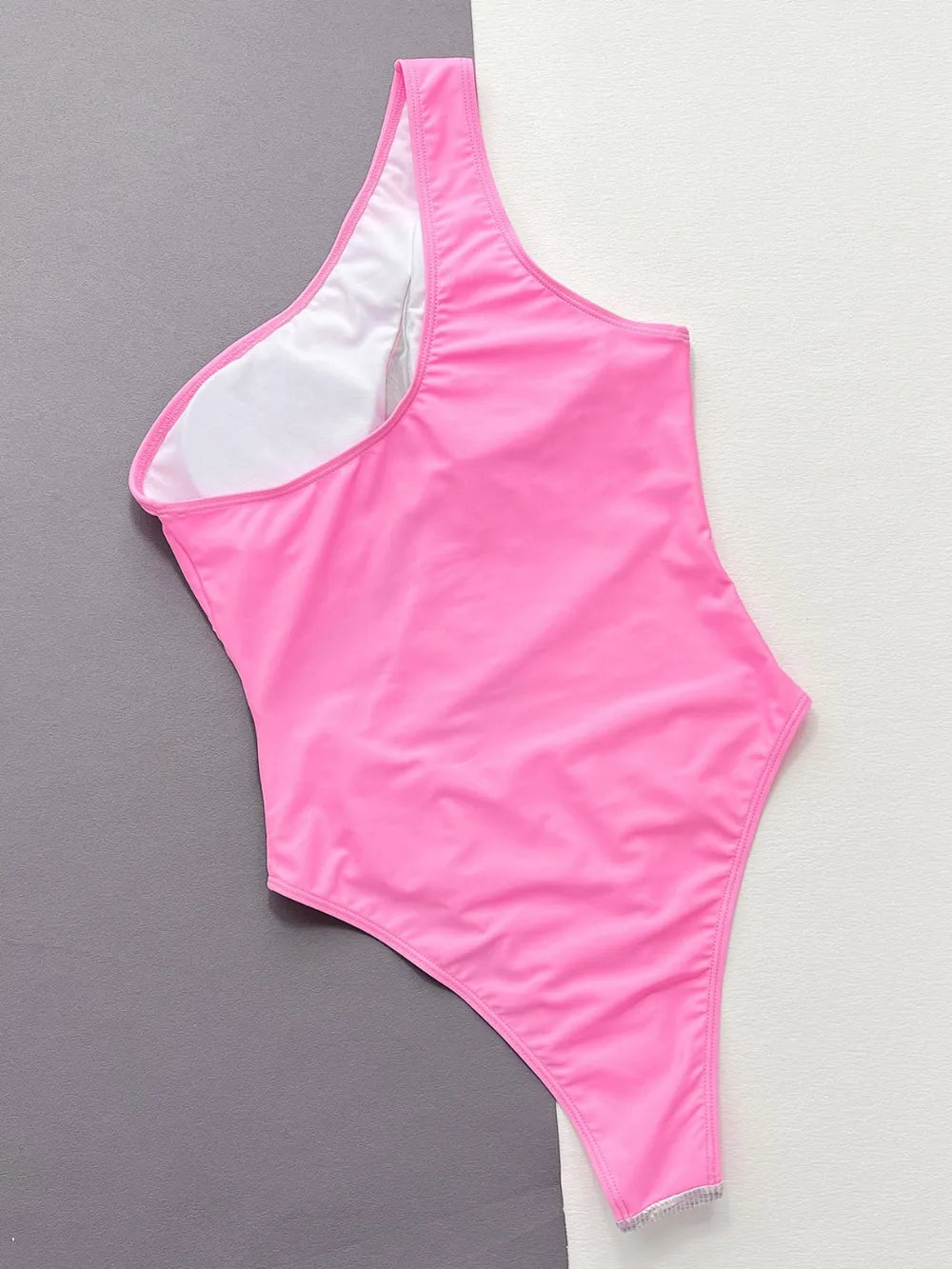 Back of the hot pink swimsuit laid flat, plain pink with white lining at the shoulder