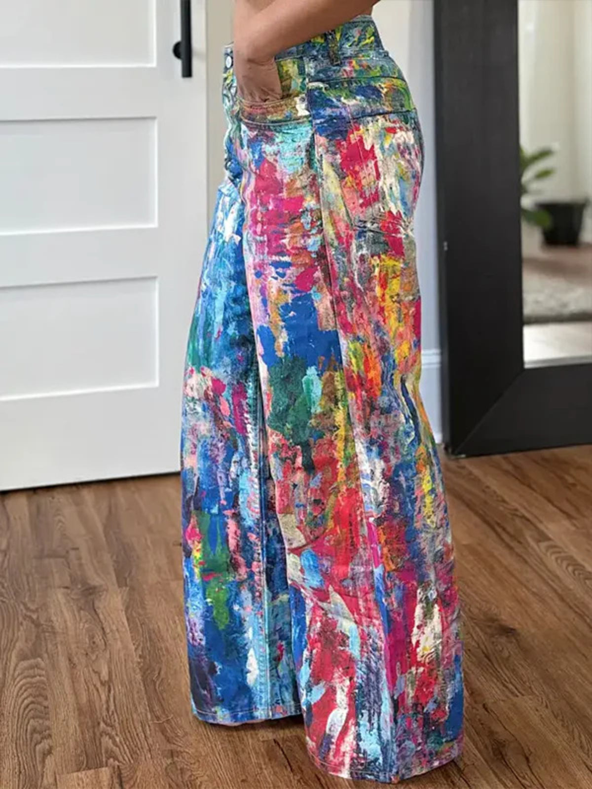 Colorful patterned pants being worn indoors on a wooden floor.