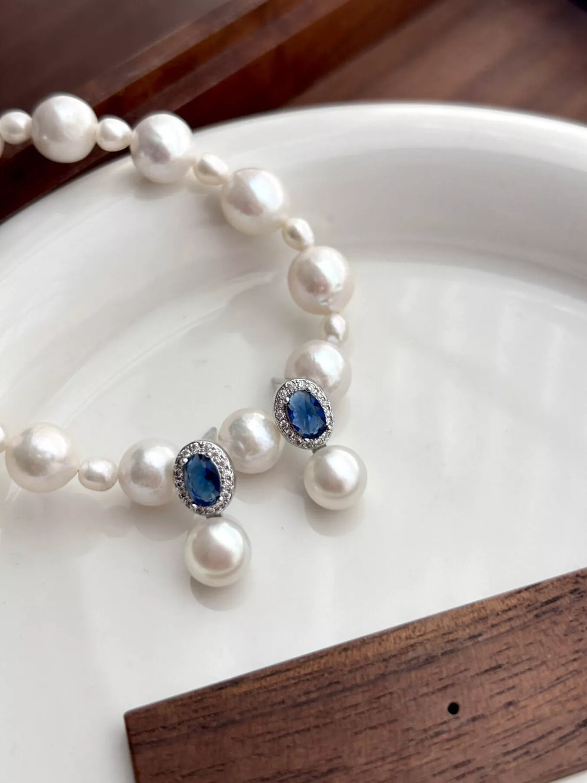 Pearl necklace with blue gemstones on a white plate