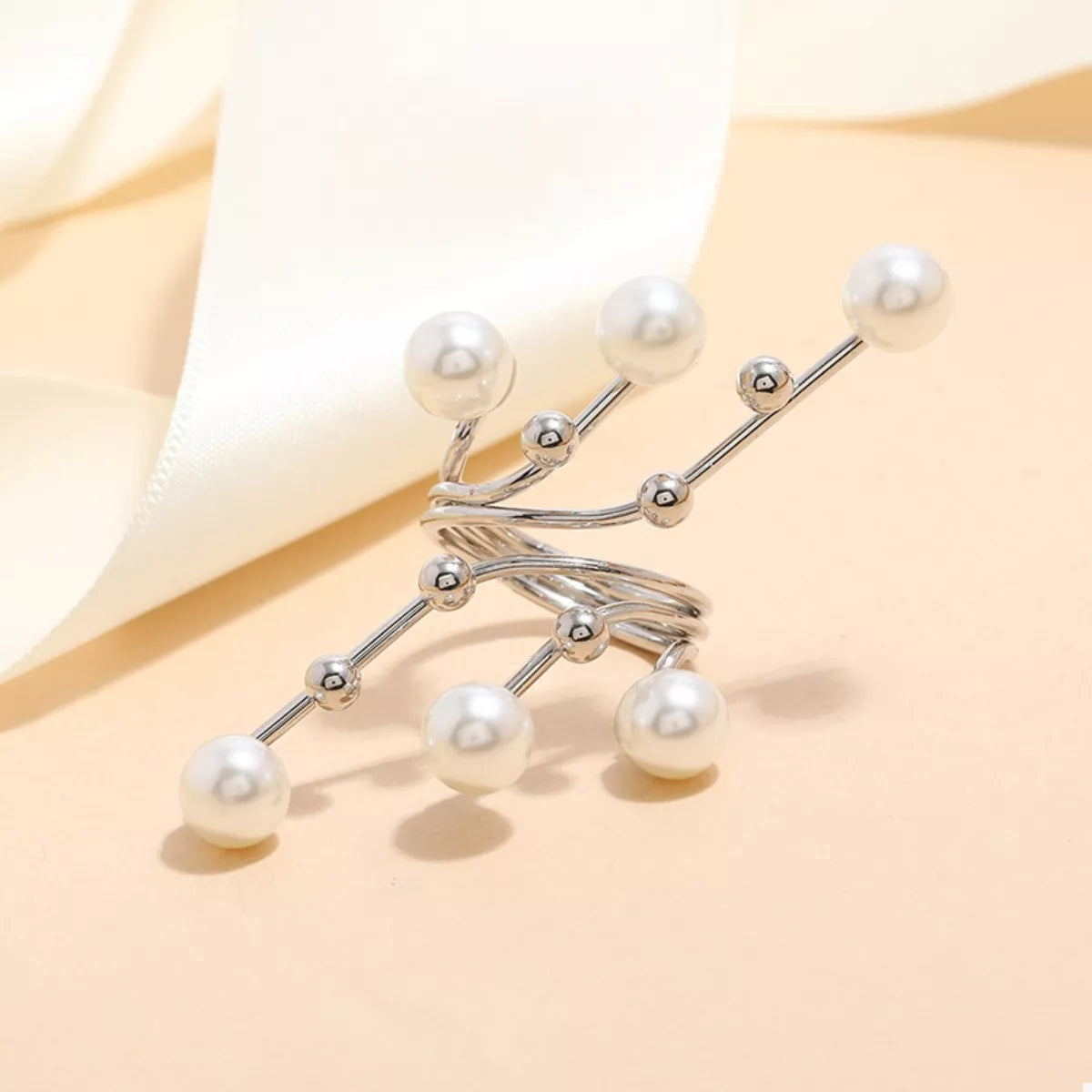 Silver brooch with pearl-like beads on a beige background