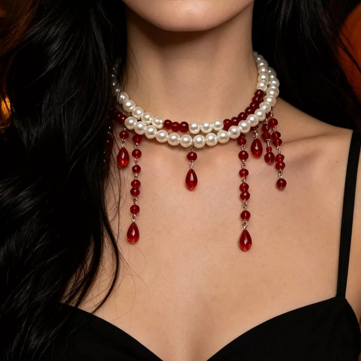 Close-up of the pearl choker with red beaded drips resting at the collarbone