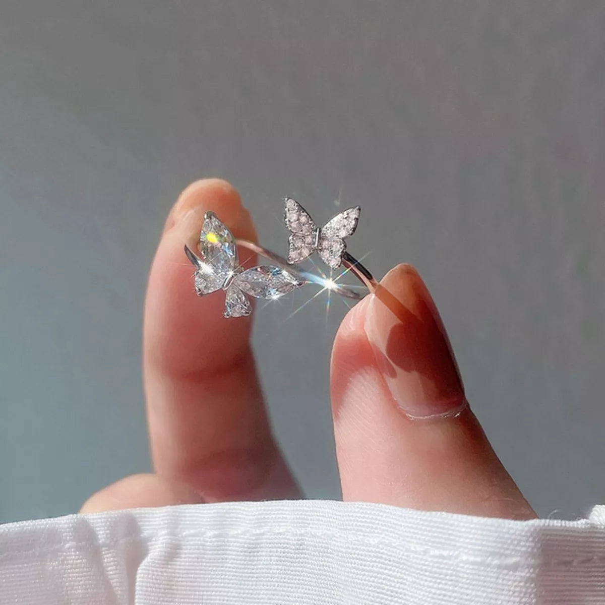 Close shot of Butterfly-shaped earrings held by a hand against a dark background
