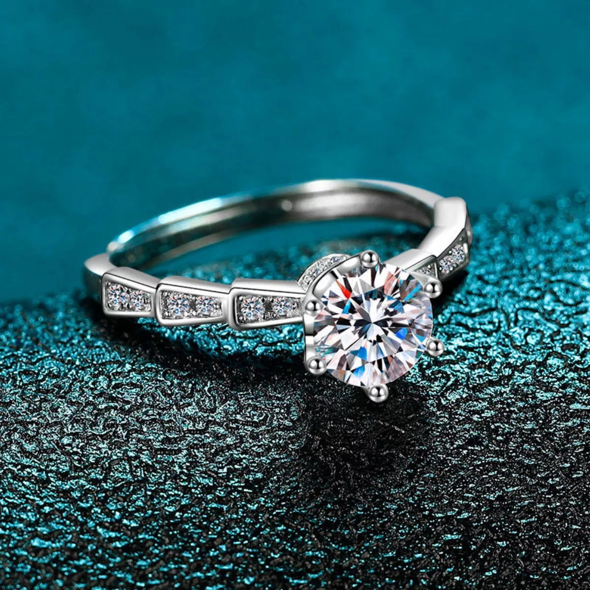 Silver ring with a large diamond on a textured blue surface